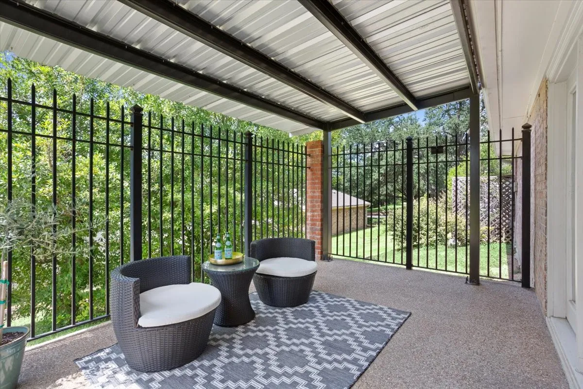 Covered back patio with a corrugated metal roof and black metal fencing
