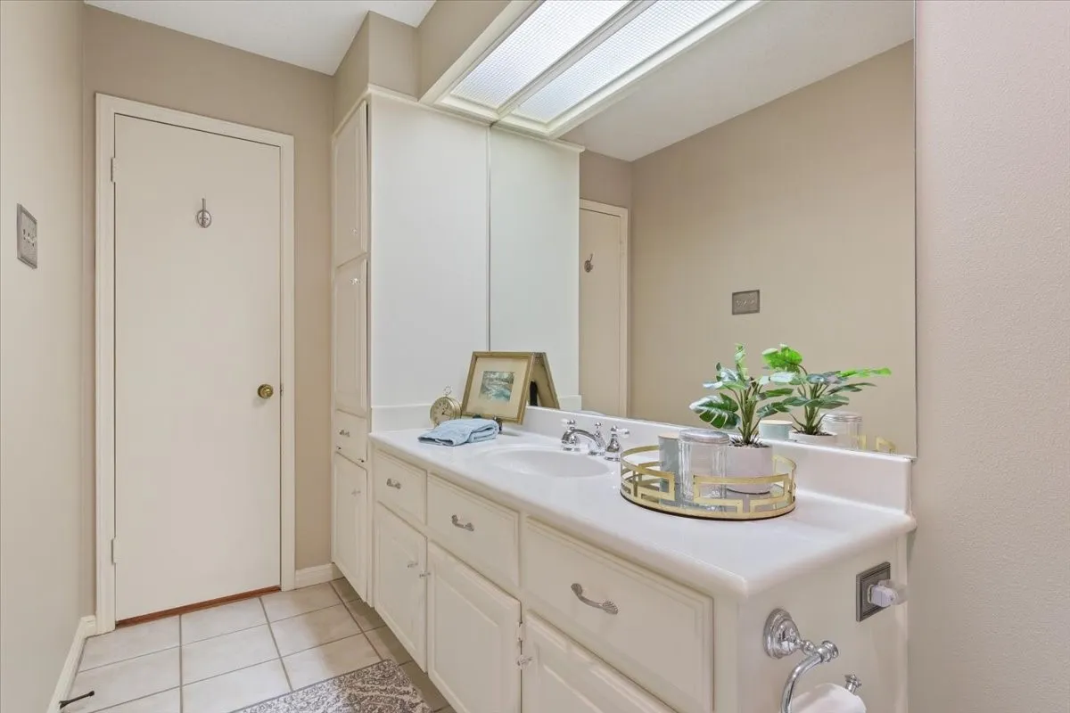 Spa-inspired guest bathroom featuring an expansive vanity, white quartz countertop and abundant storage cabinetry