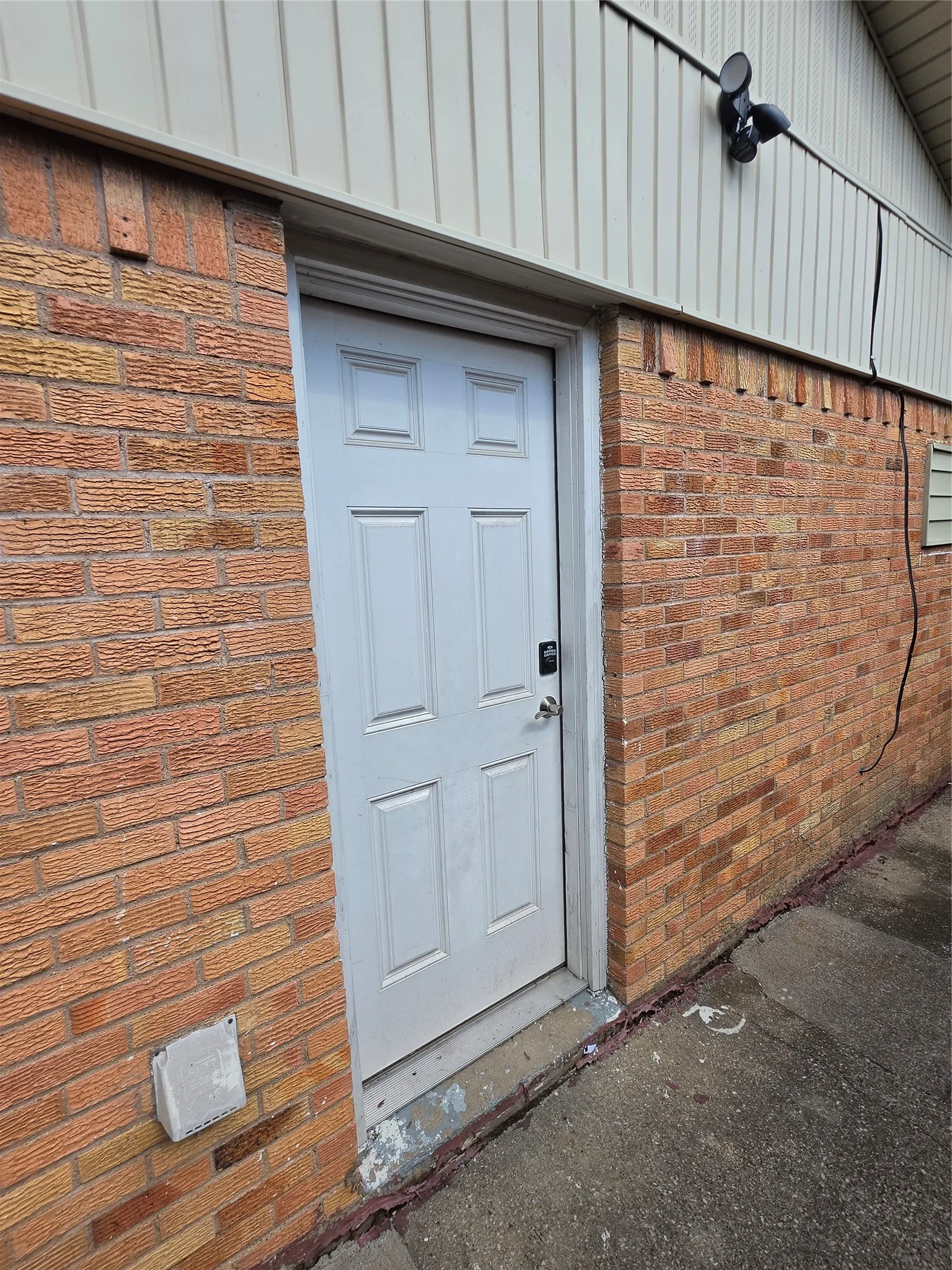 Brick exterior featuring a paneled entry door and exterior lighting fixture