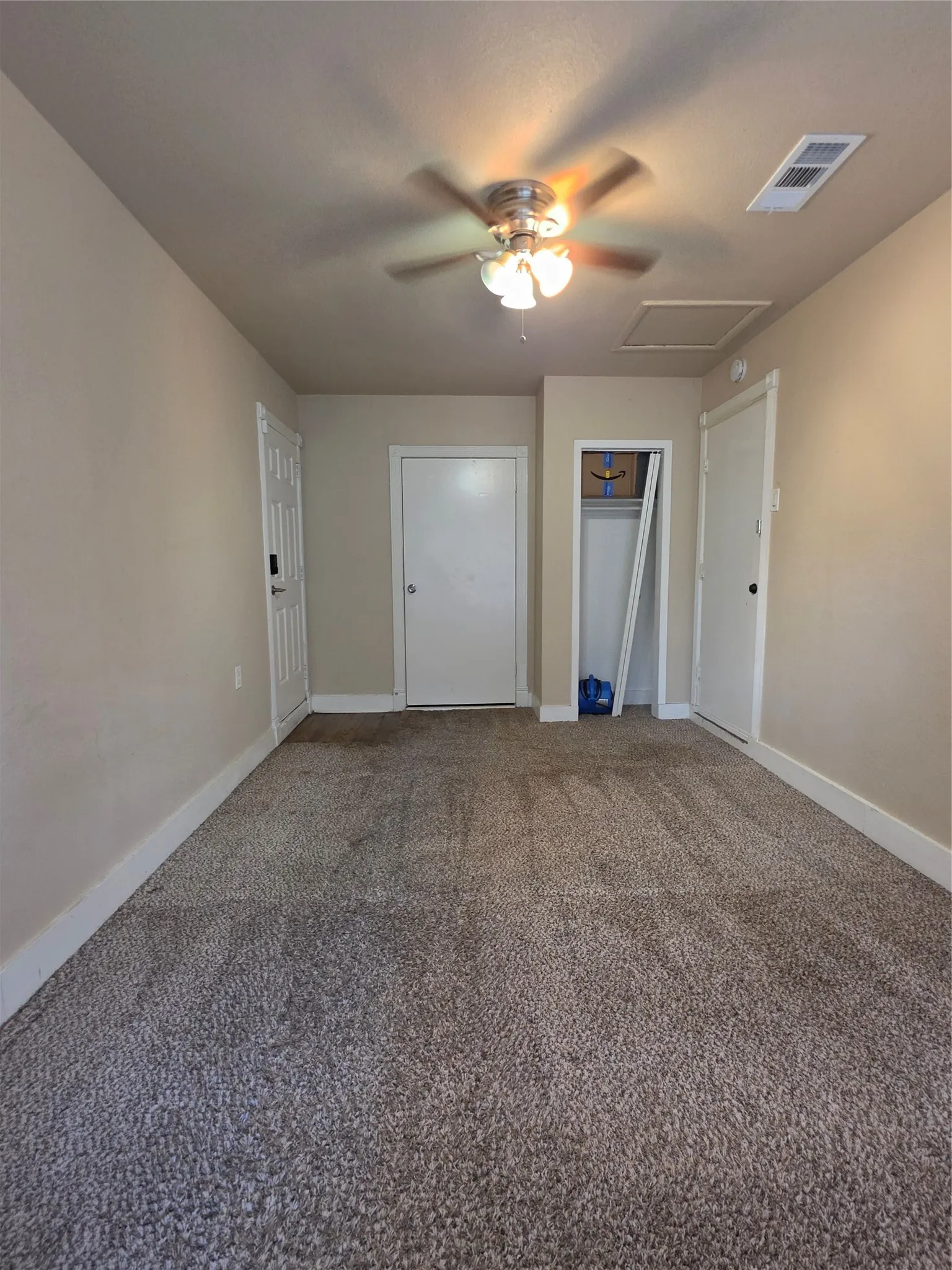 Textured carpet flooring, ceiling fan with integrated lighting, neutral wall paint, white trim, and a built-in closet