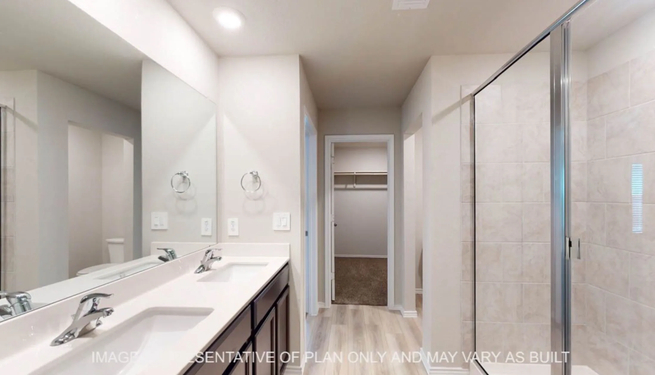 Dual-sink vanity with polished chrome faucets and rectangular vessel basins, paired with a wood-finish cabinetry base and light tile surround