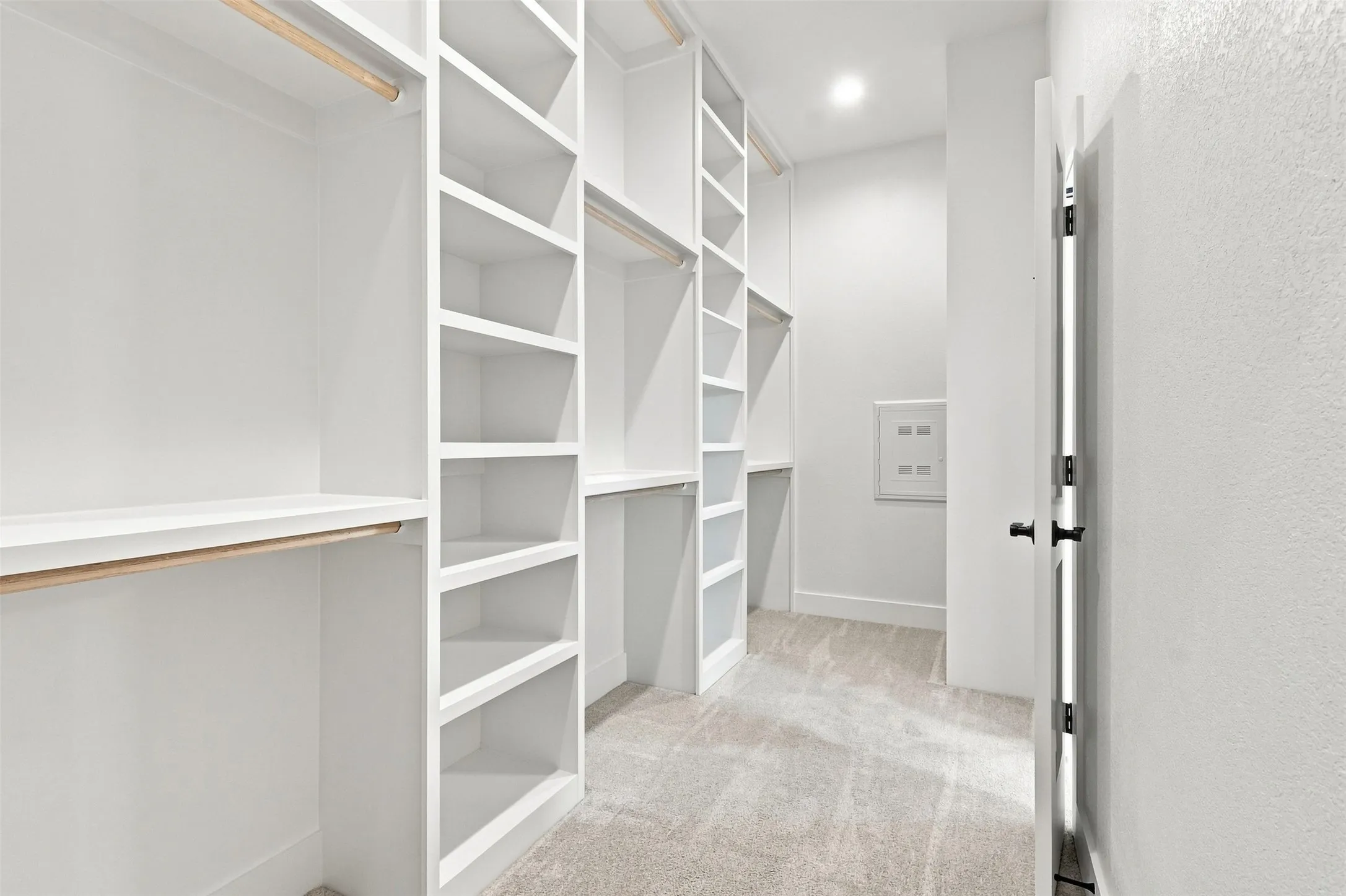 Custom built-in shelving, multiple hanging rods, recessed lighting, and carpet flooring