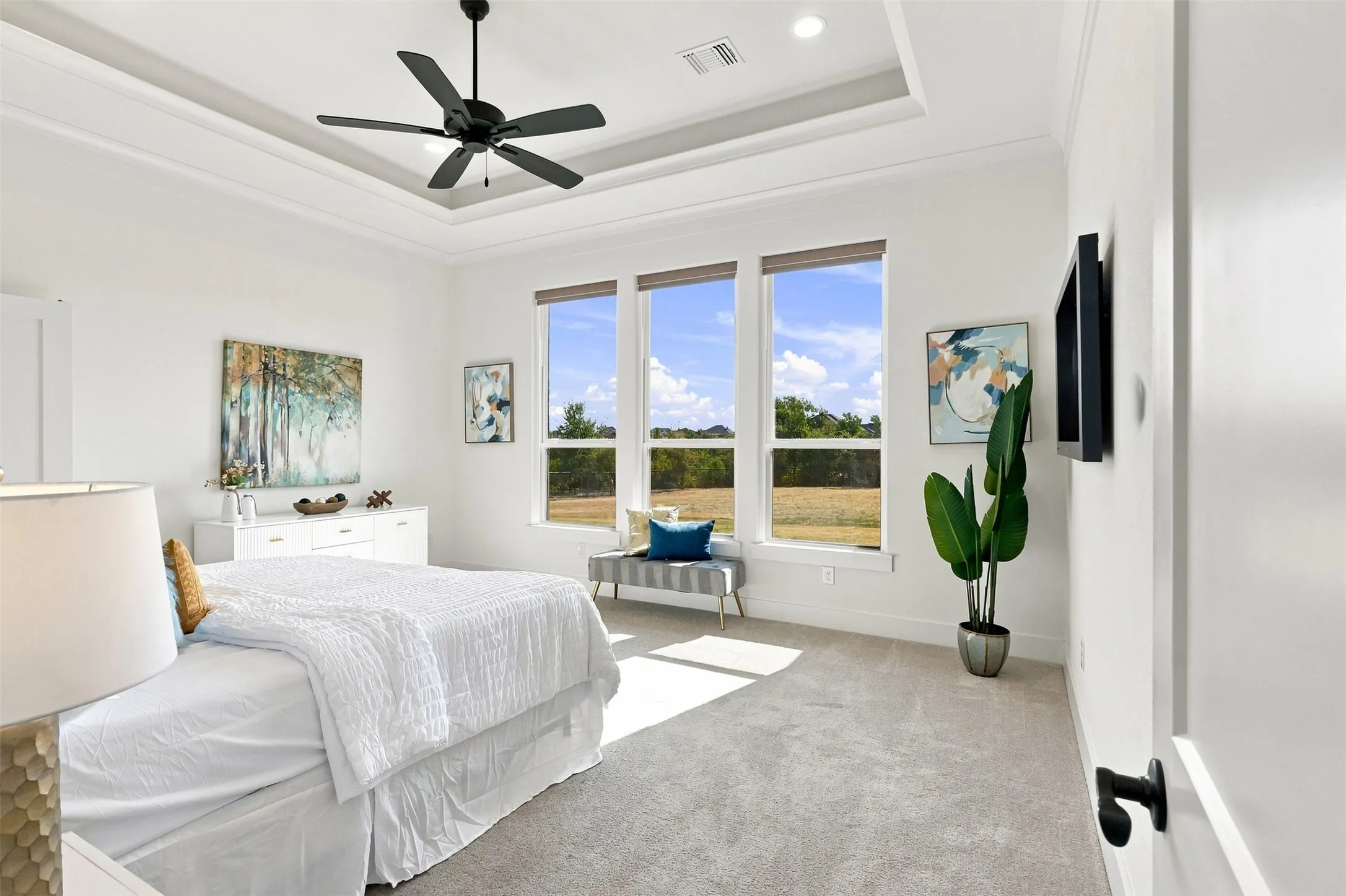 Tray ceiling with recessed lighting and a ceiling fan, three large windows, motorized blinds, and wall-to-wall carpeting