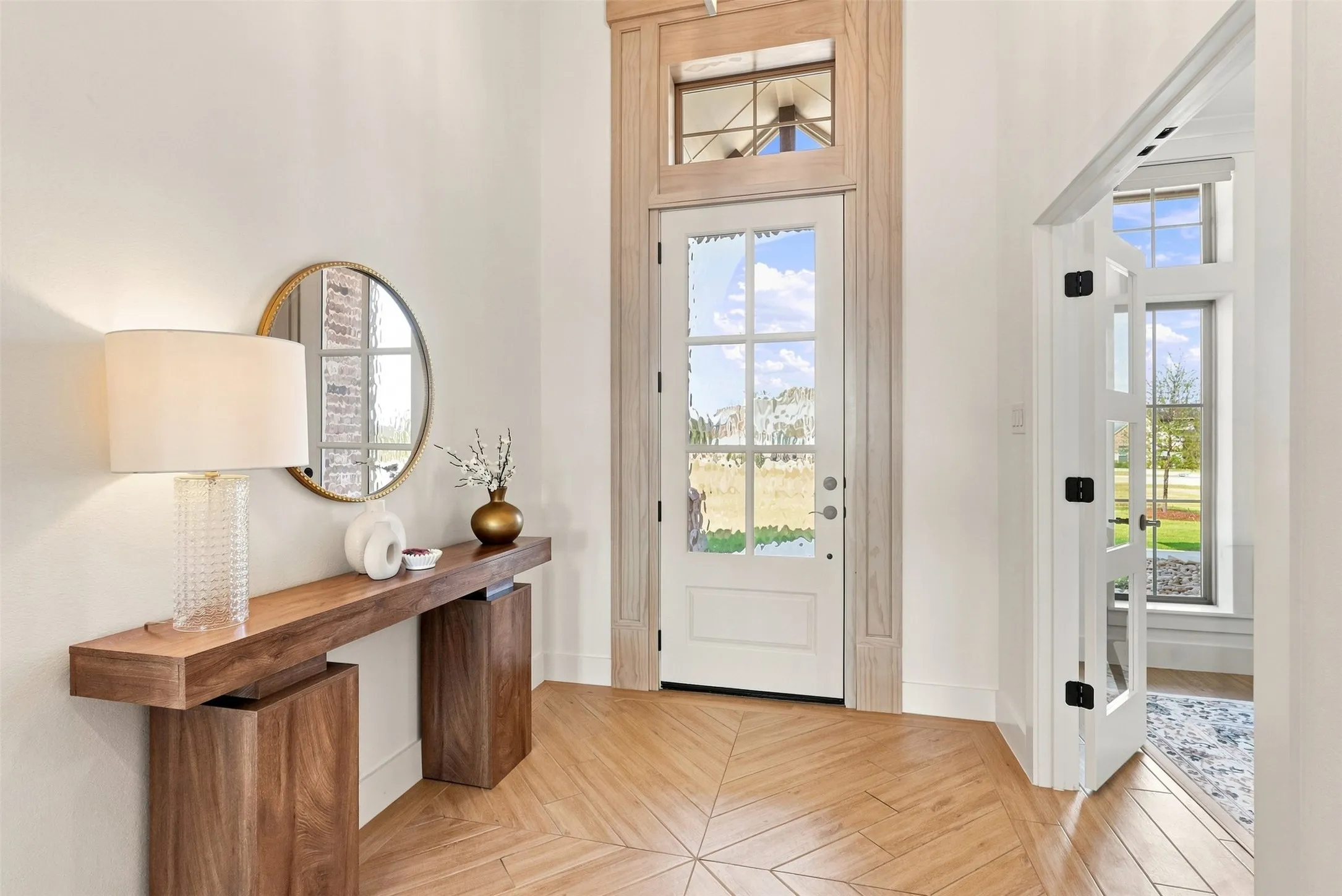 Herringbone wood-finish flooring, white walls, and a transom window above the entry door