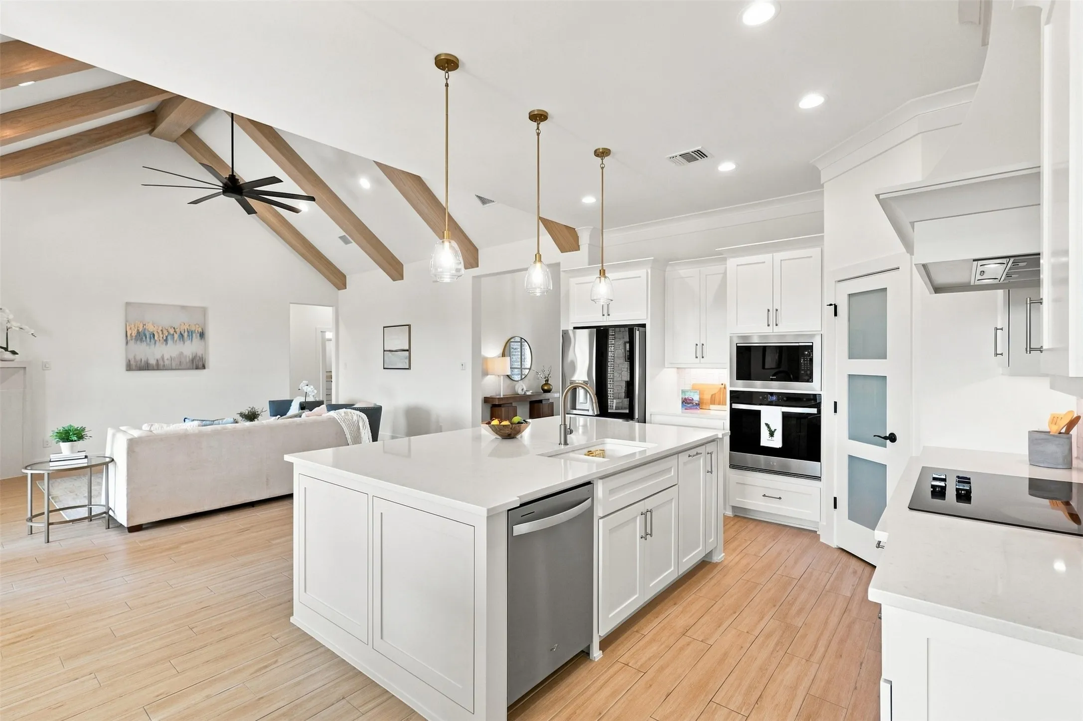 Open-concept kitchen with a large island, white cabinetry, quartz countertops, and built-in stainless steel appliances