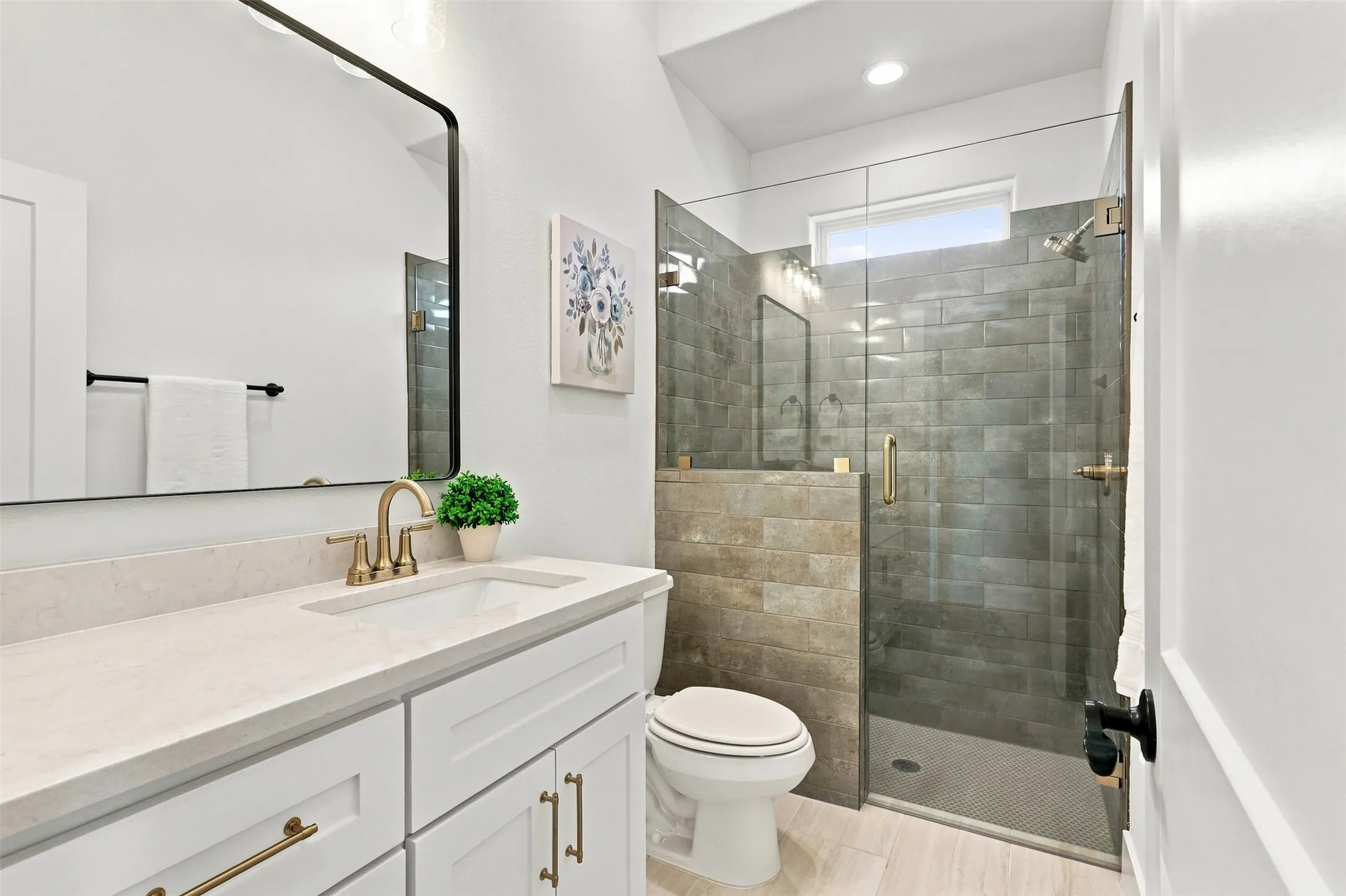 Vanity with a light-colored countertop, gold-finish faucet, and white cabinetry