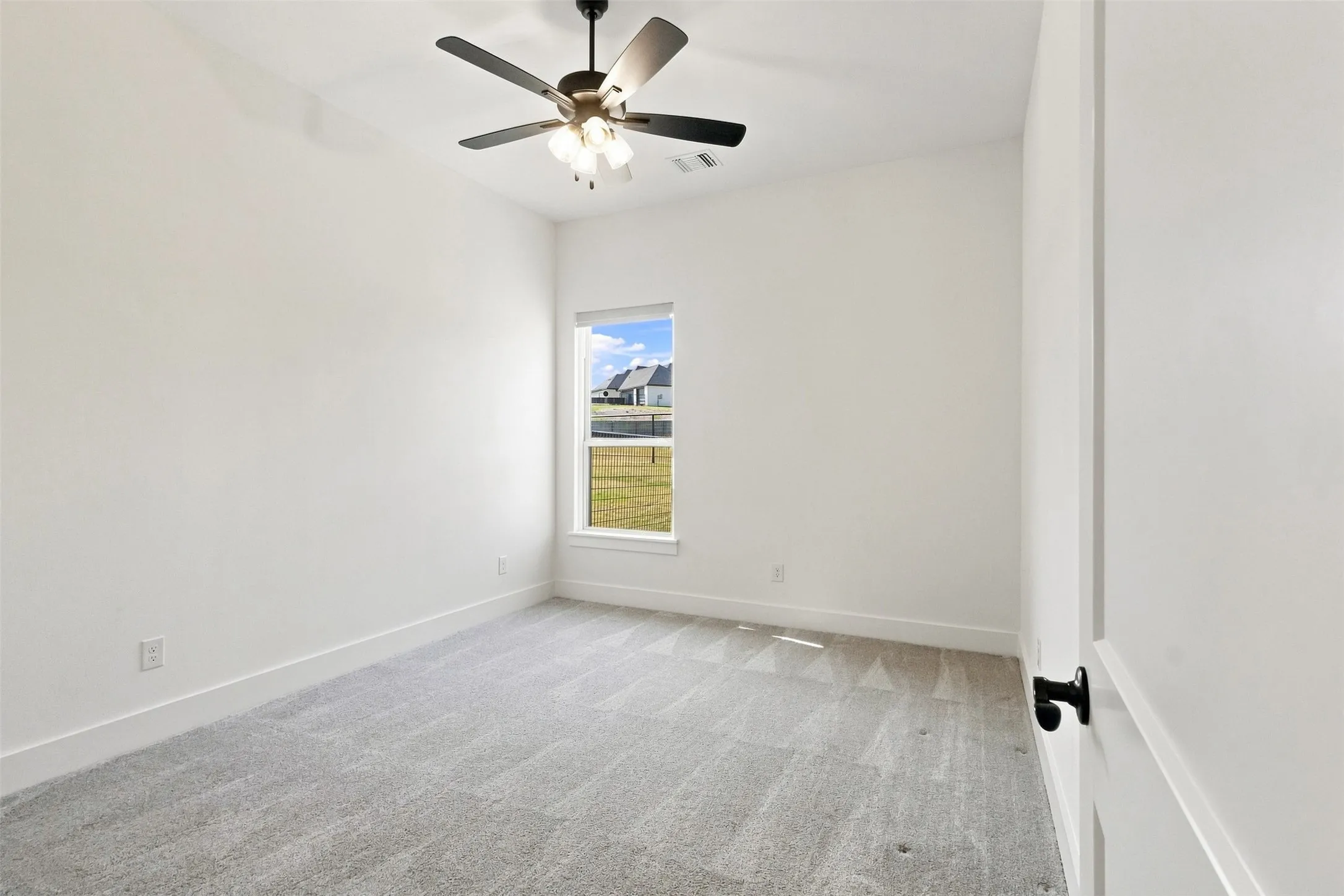 Recessed window, ceiling fan with integrated lighting, wall-to-wall carpeting, and a white interior door with matte black hardware, and motorized blinds