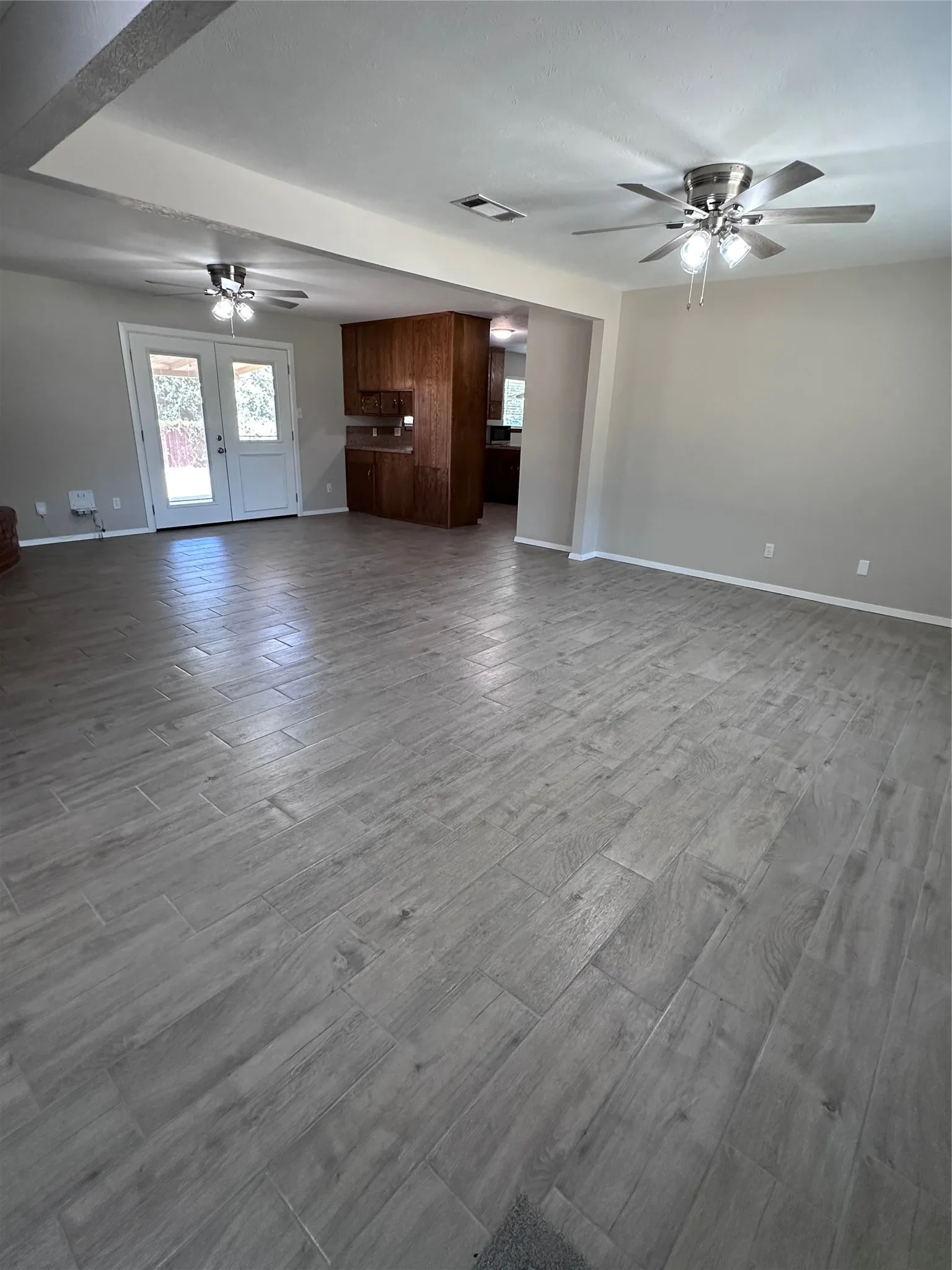Spacious open-concept living area featuring wood-look tile flooring, neutral wall tones, and recessed lighting