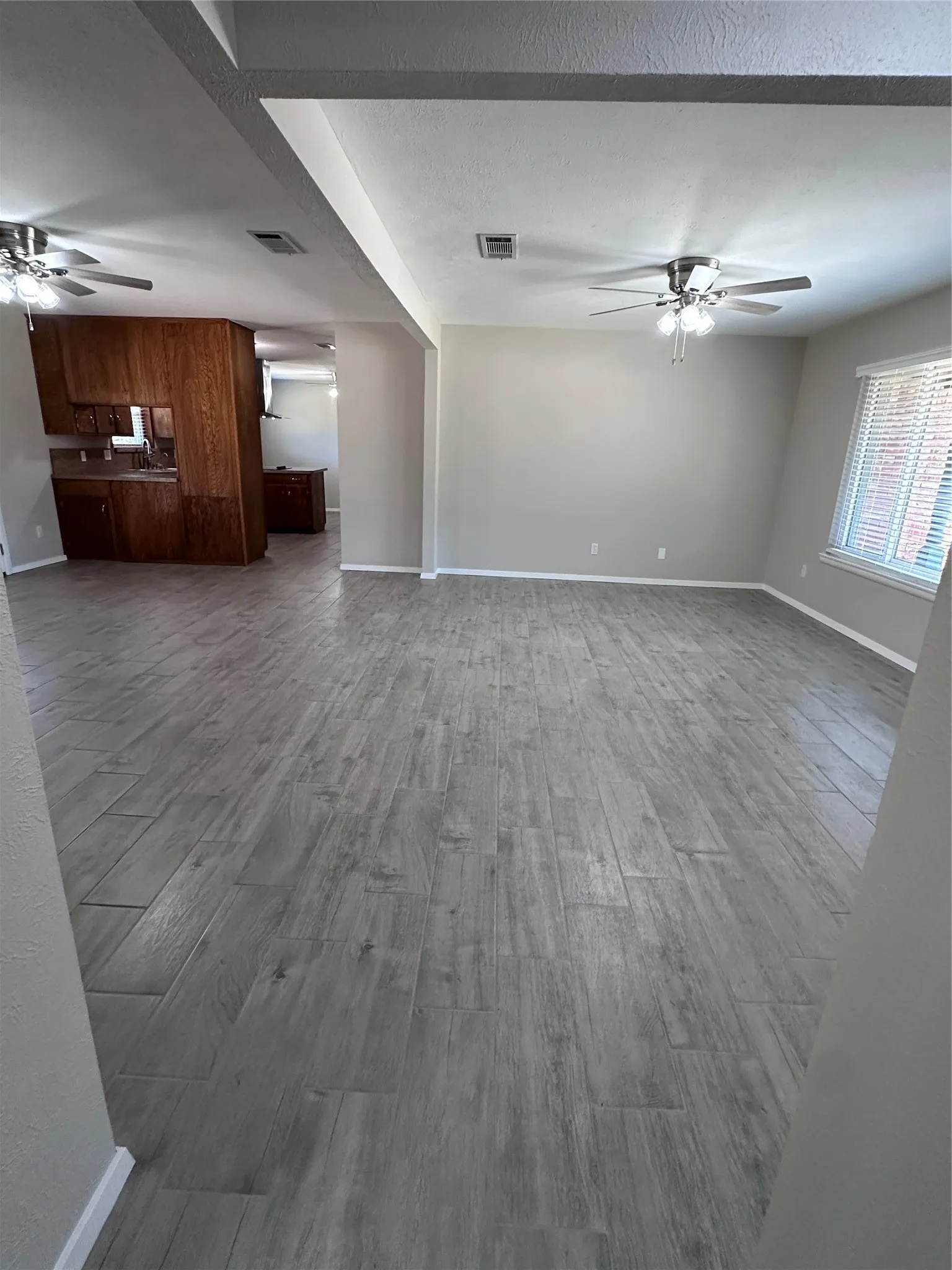 Wood-finish flooring throughout, neutral wall paint, white trim, and ceiling fans with integrated lighting