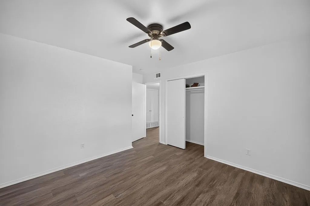Wood-finish flooring with white walls and a ceiling fan