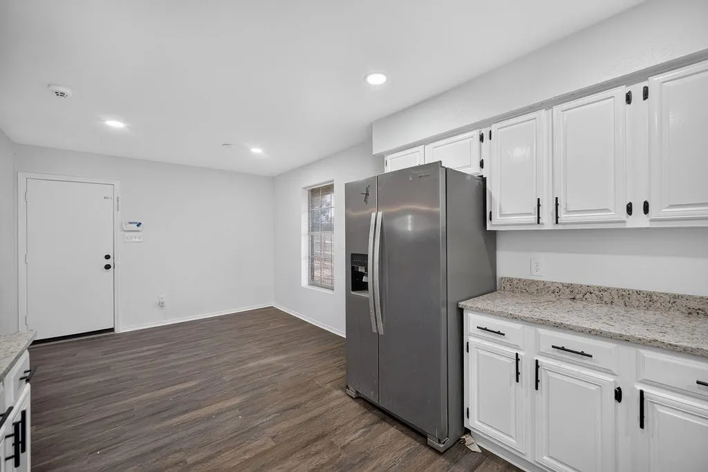 Galley kitchen featuring white cabinetry, light-toned countertops, and wood-finish flooring
