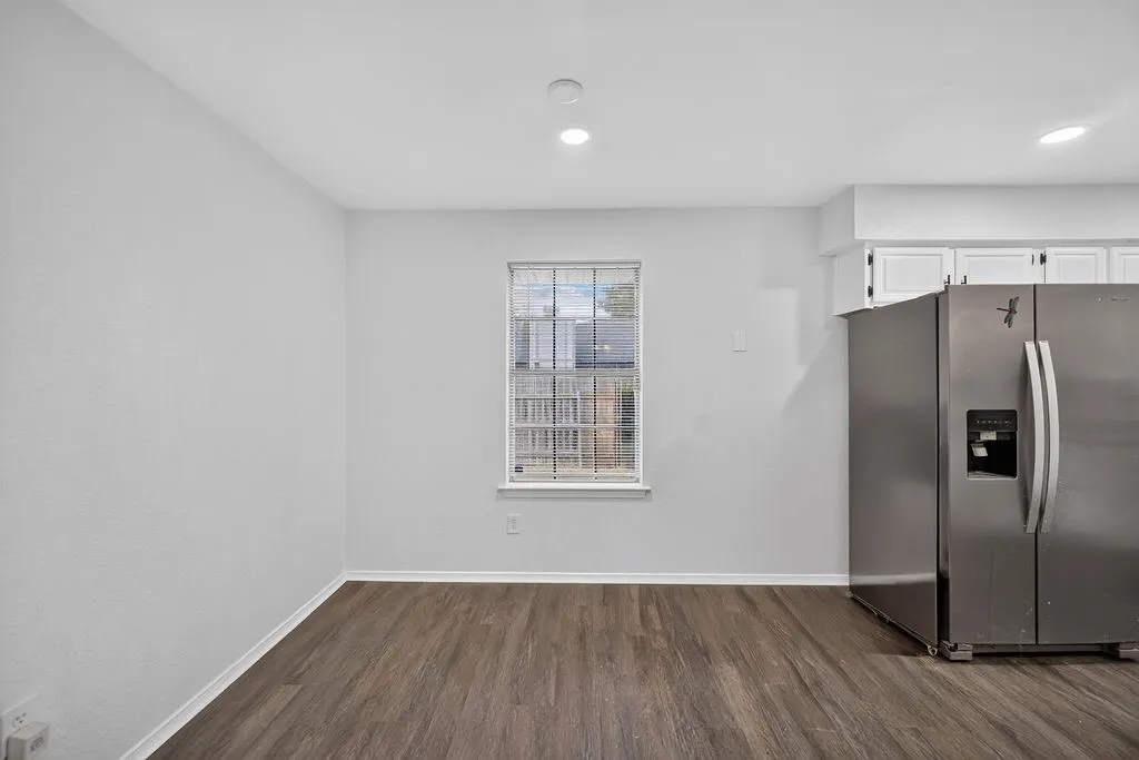 Wood-finish flooring, white walls, and a window with white trim