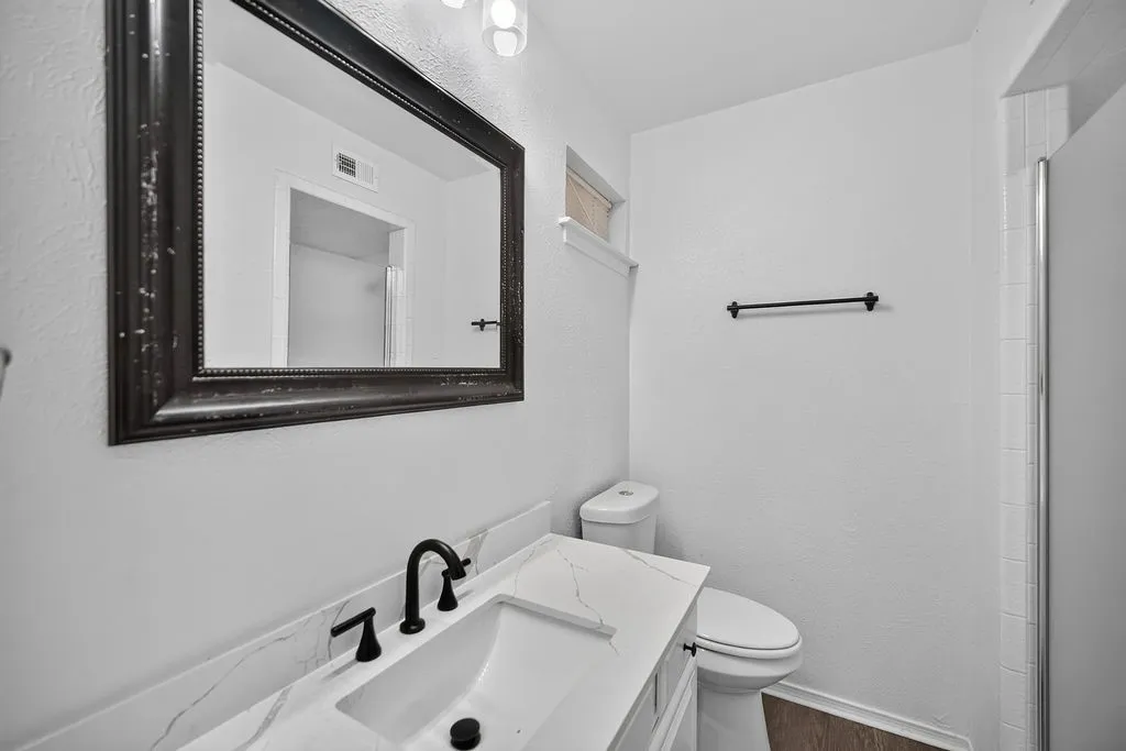 White vanity with a rectangular undermount sink, black faucet, and patterned countertop