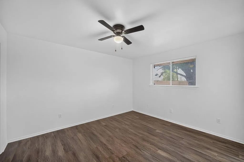 Room featuring wood-finish flooring and a ceiling fan with integrated lighting