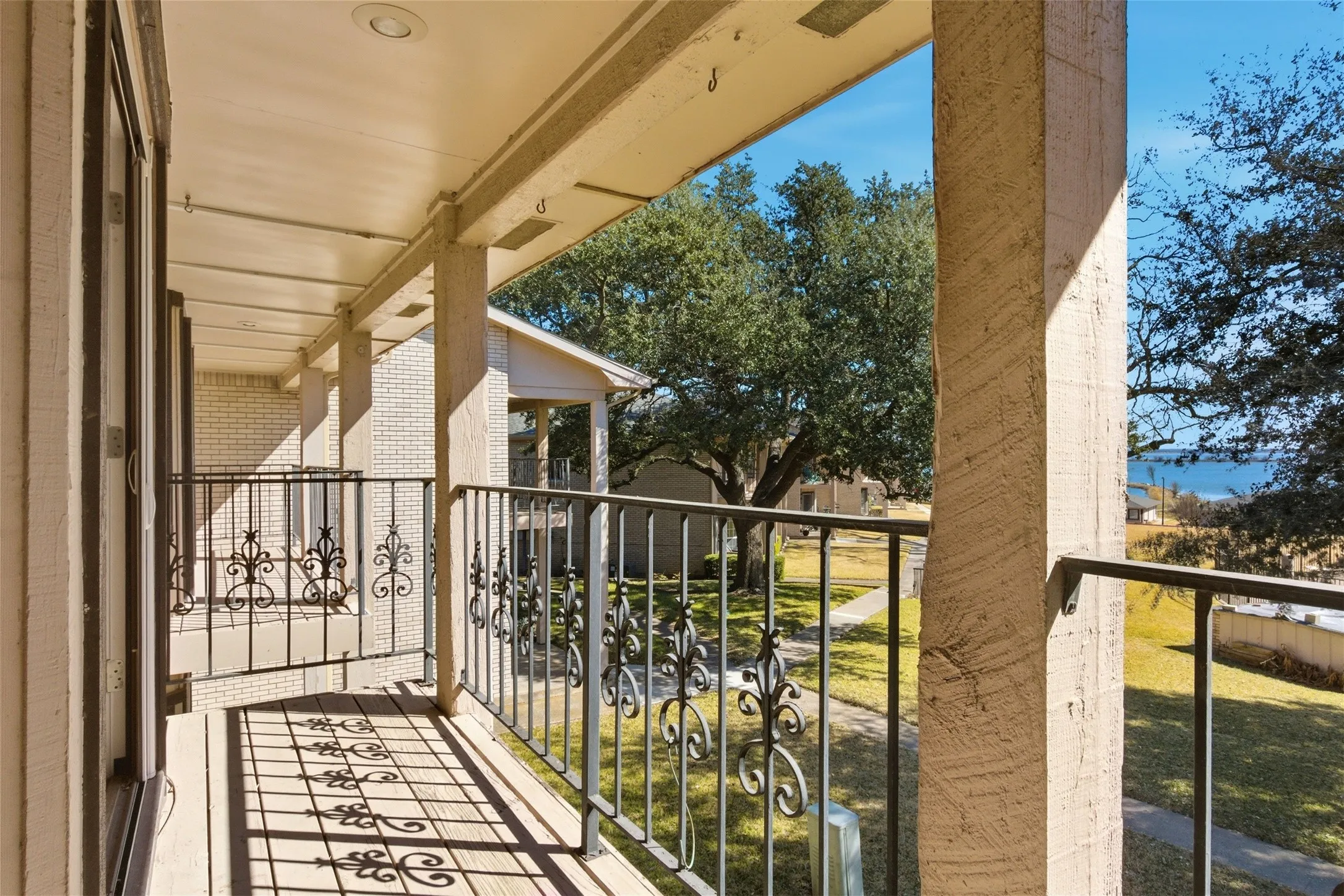 Private balcony with ornamental wrought iron railing, wood-finish flooring, and recessed lighting