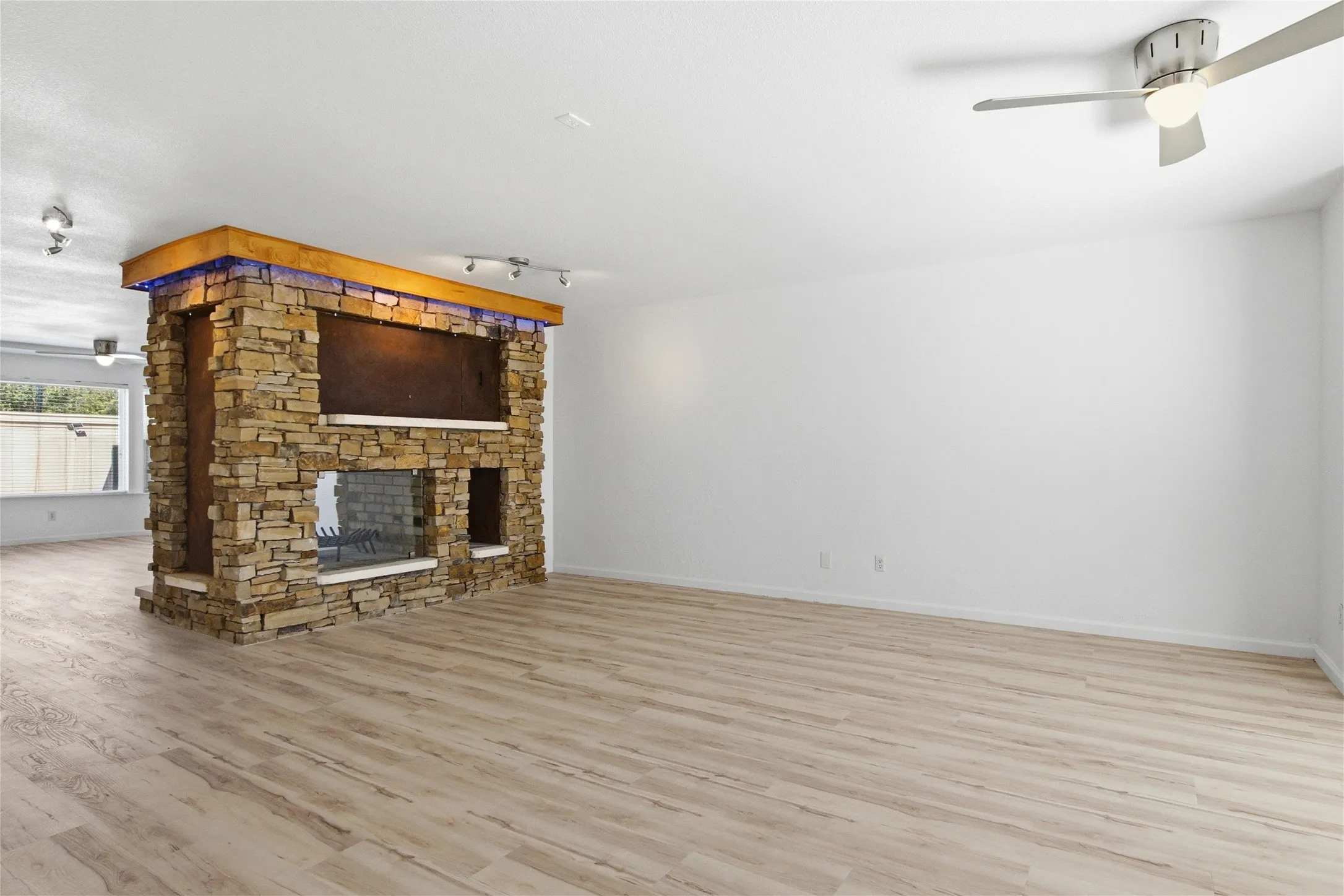 Stone-clad fireplace with glass enclosure, integrated lighting, and a wood mantel