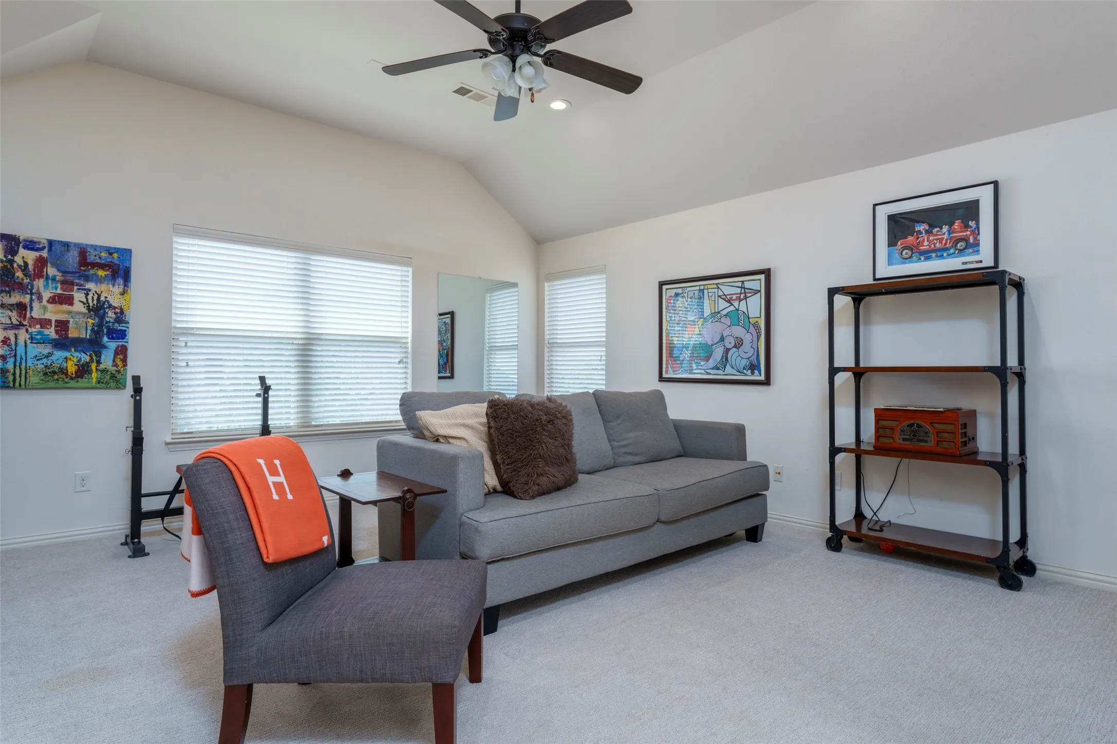 Upstairs Living Room: Versatile upstairs living space filled with natural light from a wall of windows. Neutral carpeting, a ceiling fan, and generous room to create a comfortable game room, media room, playroom, or second living area. A dedicated closet adds valuable storage and flexibility for a variety of uses.