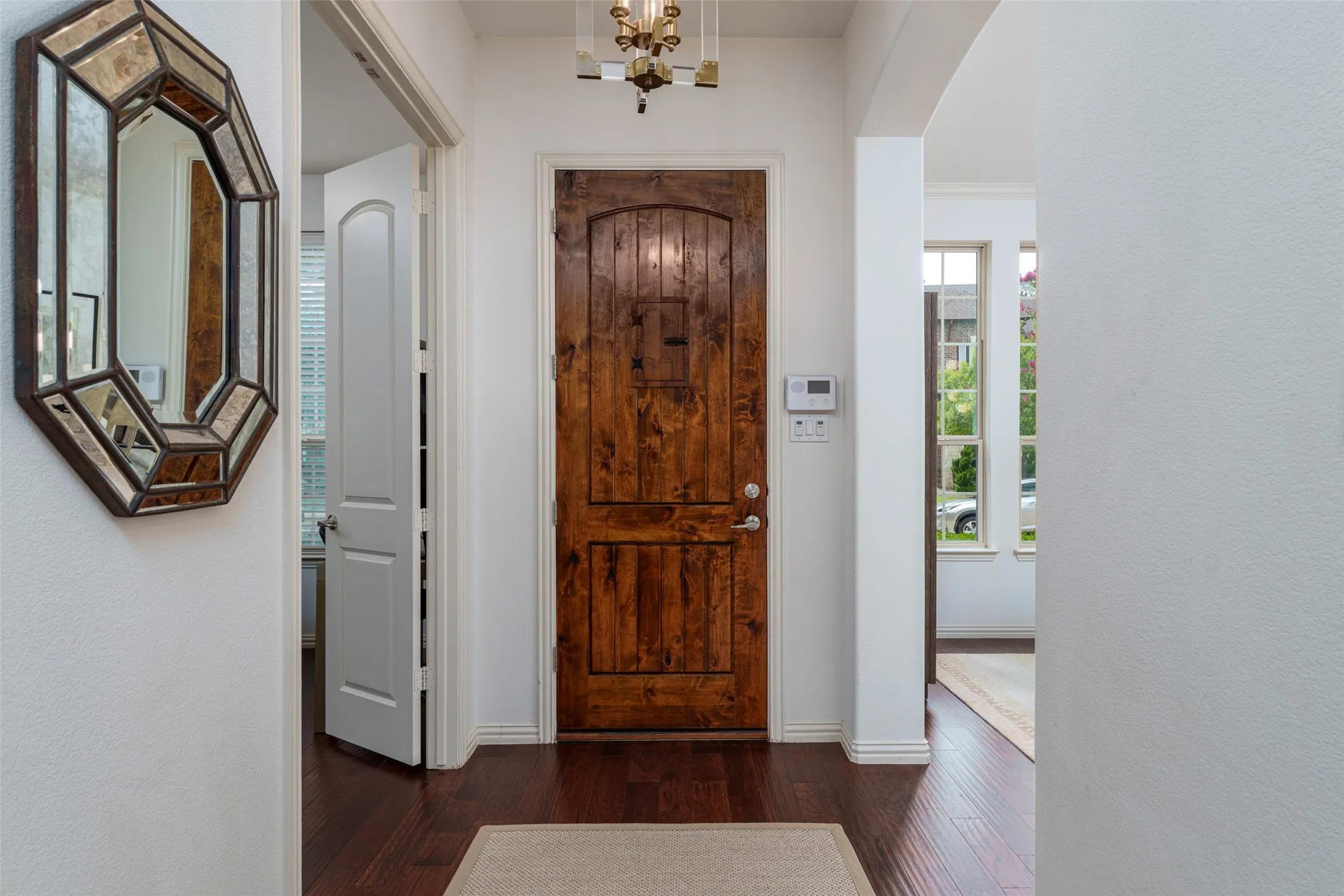 Light and bright entry welcomes you with rich wood floors, soaring ceilings, and an impressive custom wood front door. An open, airy floor plan, crisp neutral walls, elegant architectural details, and abundant natural light create a warm and inviting first impression. The spacious entry provides a seamless transition to the home's beautifully appointed living spaces.