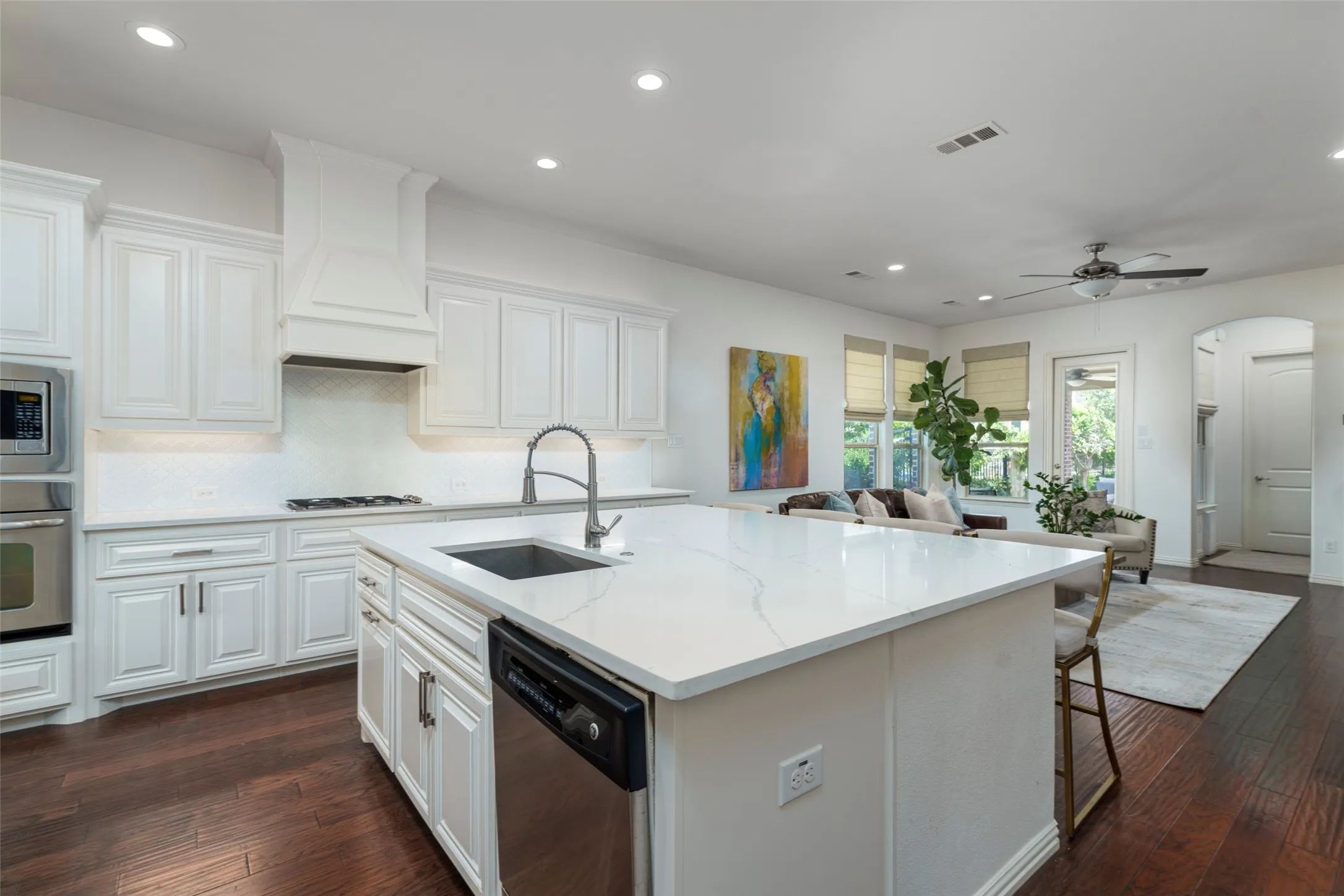 Recently updated open-concept kitchen features crisp white shaker cabinets, elegant white quartz countertops, stainless steel appliances, and a huge squared-off island with abundant seating—perfect for entertaining and gathering. Rich wood floors flow throughout the space, while the bright, airy design and open sightlines create seamless connection to the dining and living areas. A beautifully updated Viridian kitchen in Arlington, TX, designed for both everyday living and entertaining.