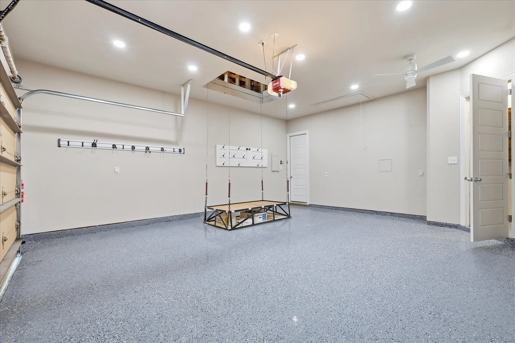 Garage space with epoxy flooring and attic lift, recessed lighting, and a ceiling fan