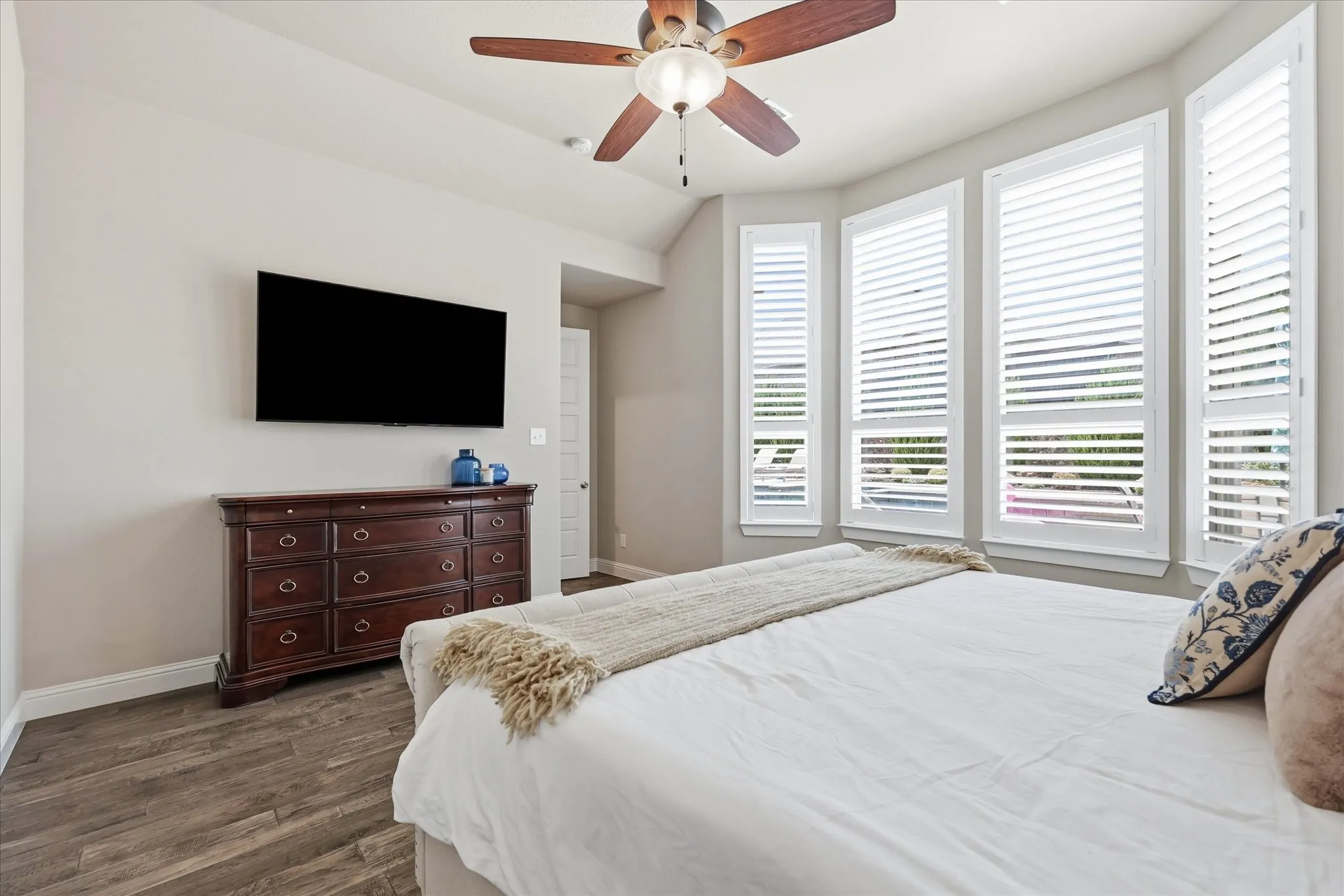Wood-finish flooring, bay window with plantation shutters, ceiling fan, and recessed lighting