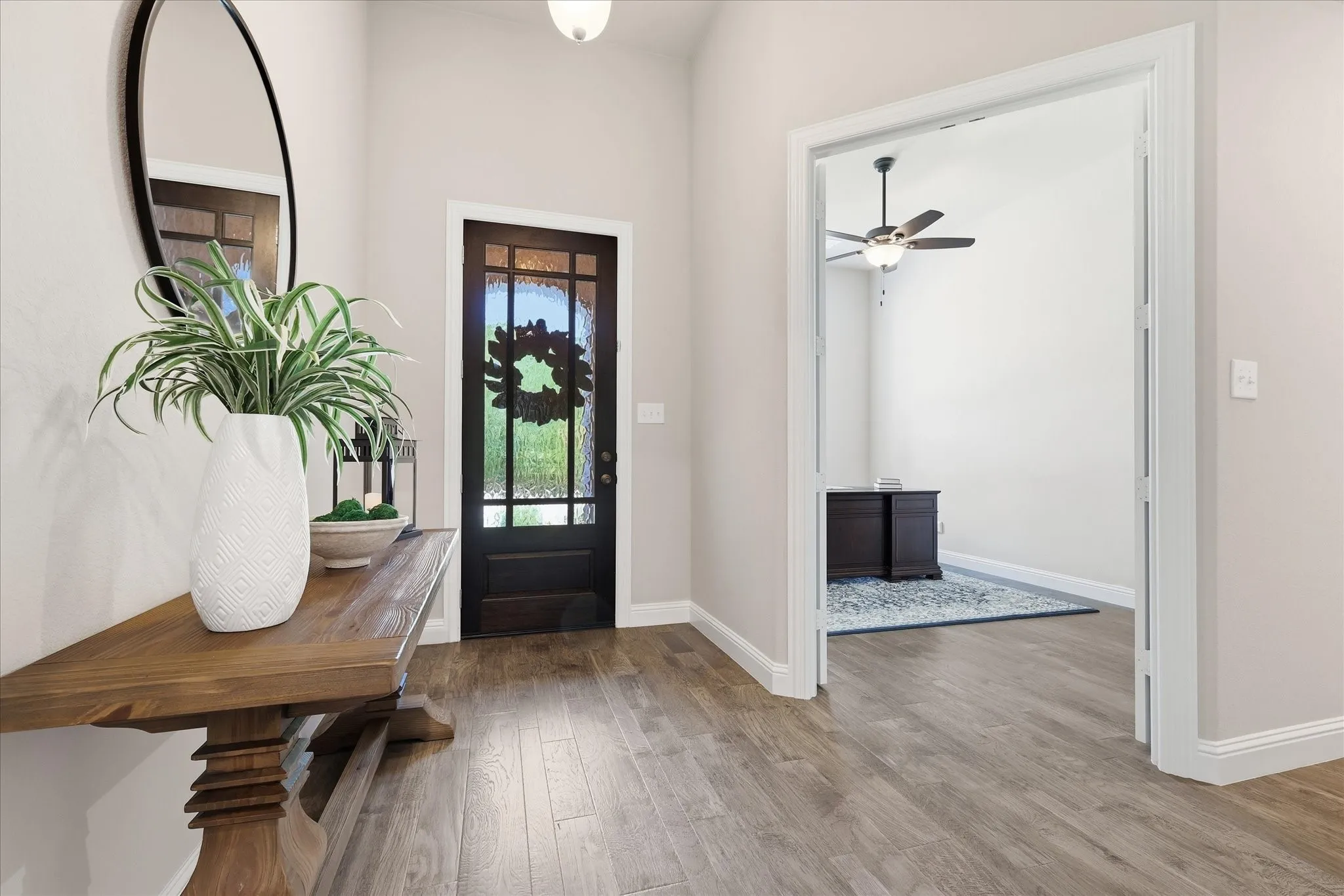 Wood-finish flooring throughout, dark wood-paneled door with frosted glass, and a built-in overhead light fixture