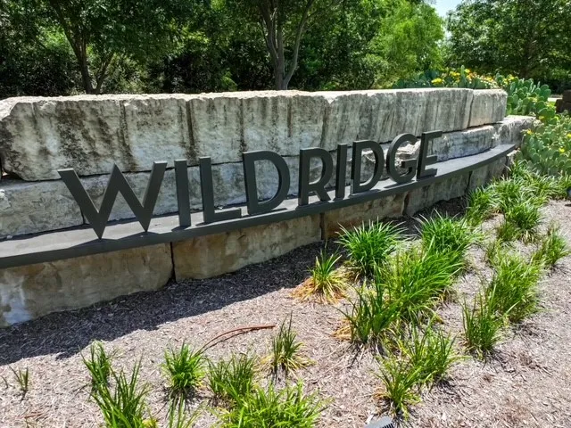 Stone wall with raised metal lettering, surrounded by manicured landscaping