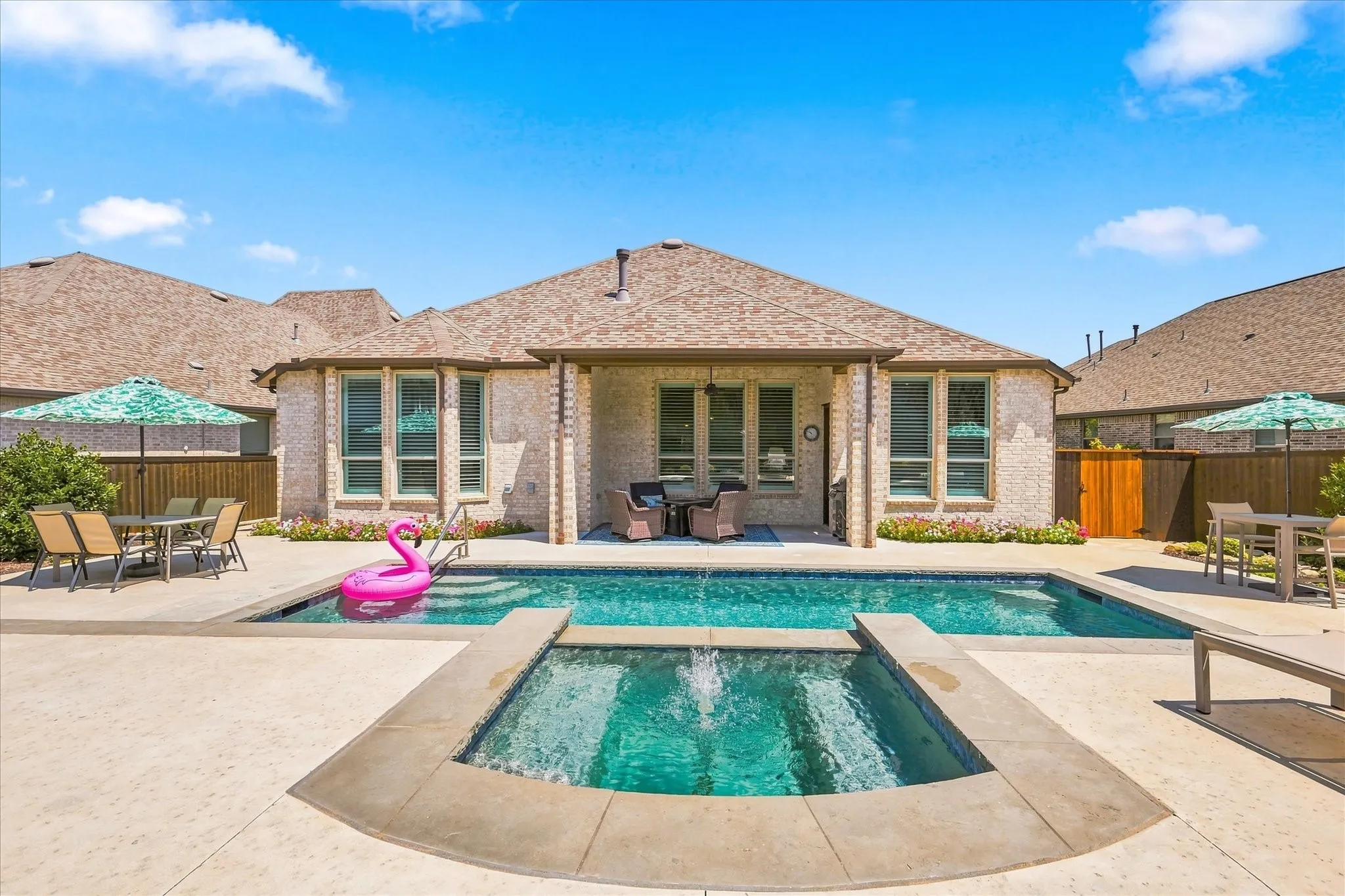 Expansive backyard featuring a large swimming pool, integrated spa, and a covered patio