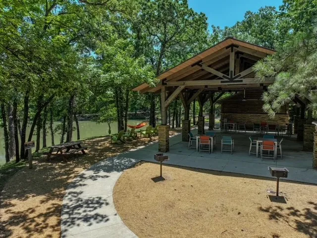 Covered pavilion with exposed wood beams, stone columns, and an adjacent water feature
