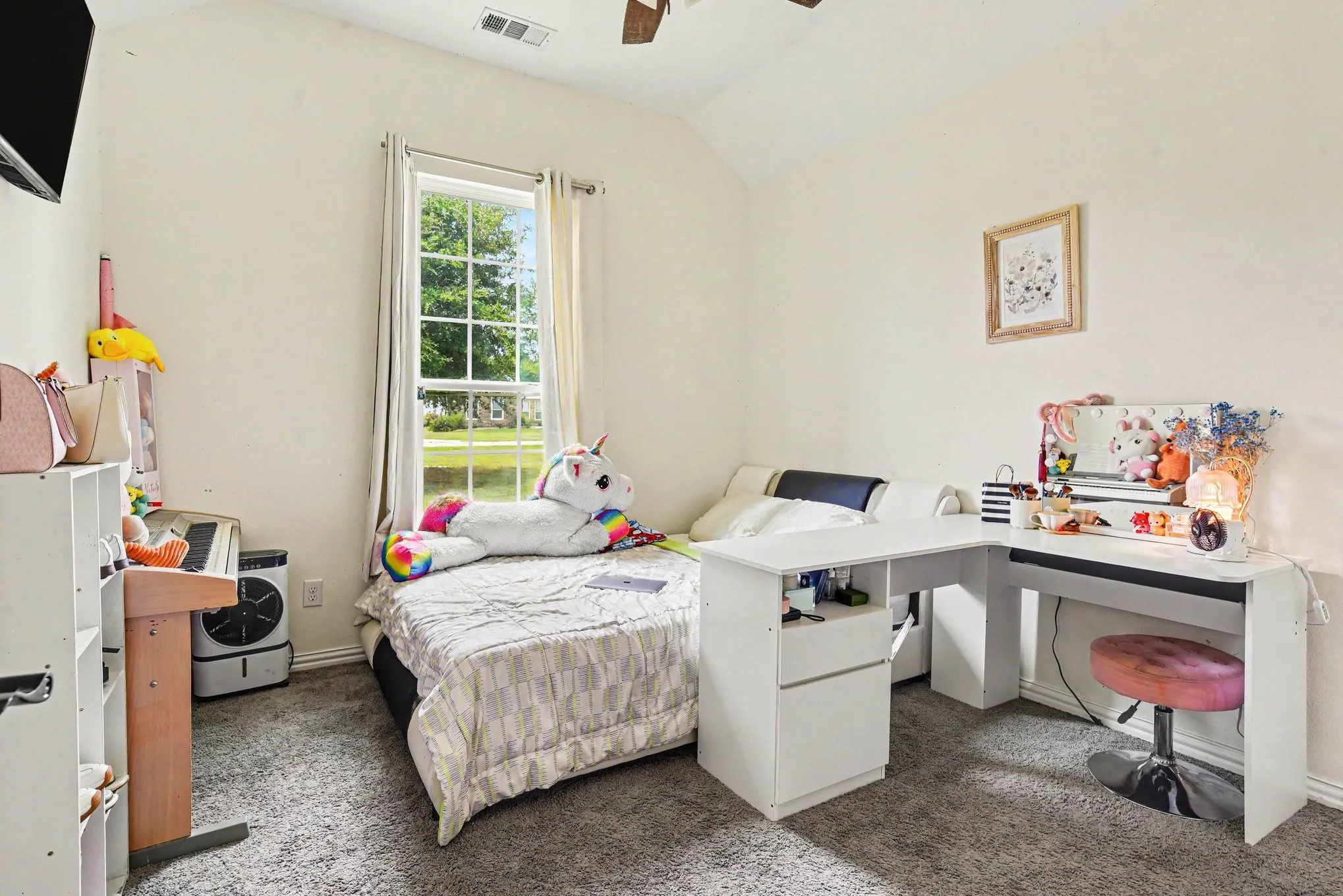 Vaulted ceiling, window with exterior landscaping, ceiling fan, and carpet flooring