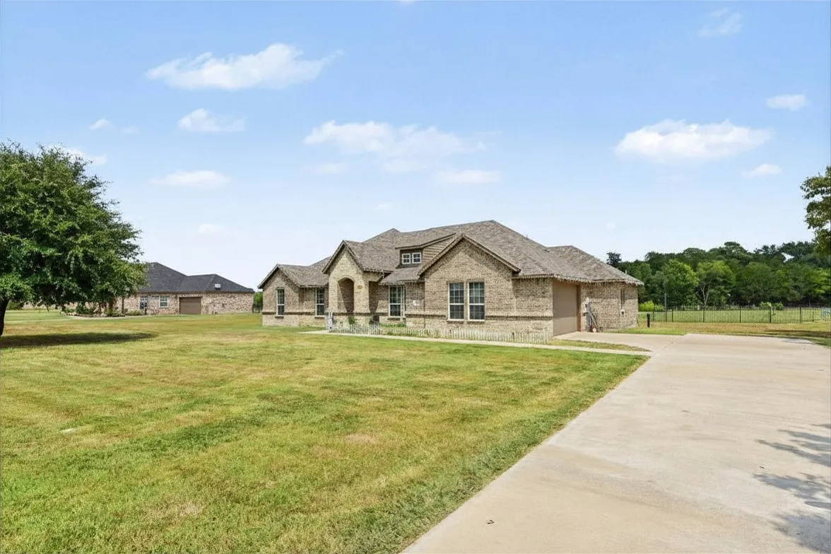 Stunning stone and stucco residence sited on expansive grounds featuring manicured lawns, mature landscaping, and a long concrete driveway approach
