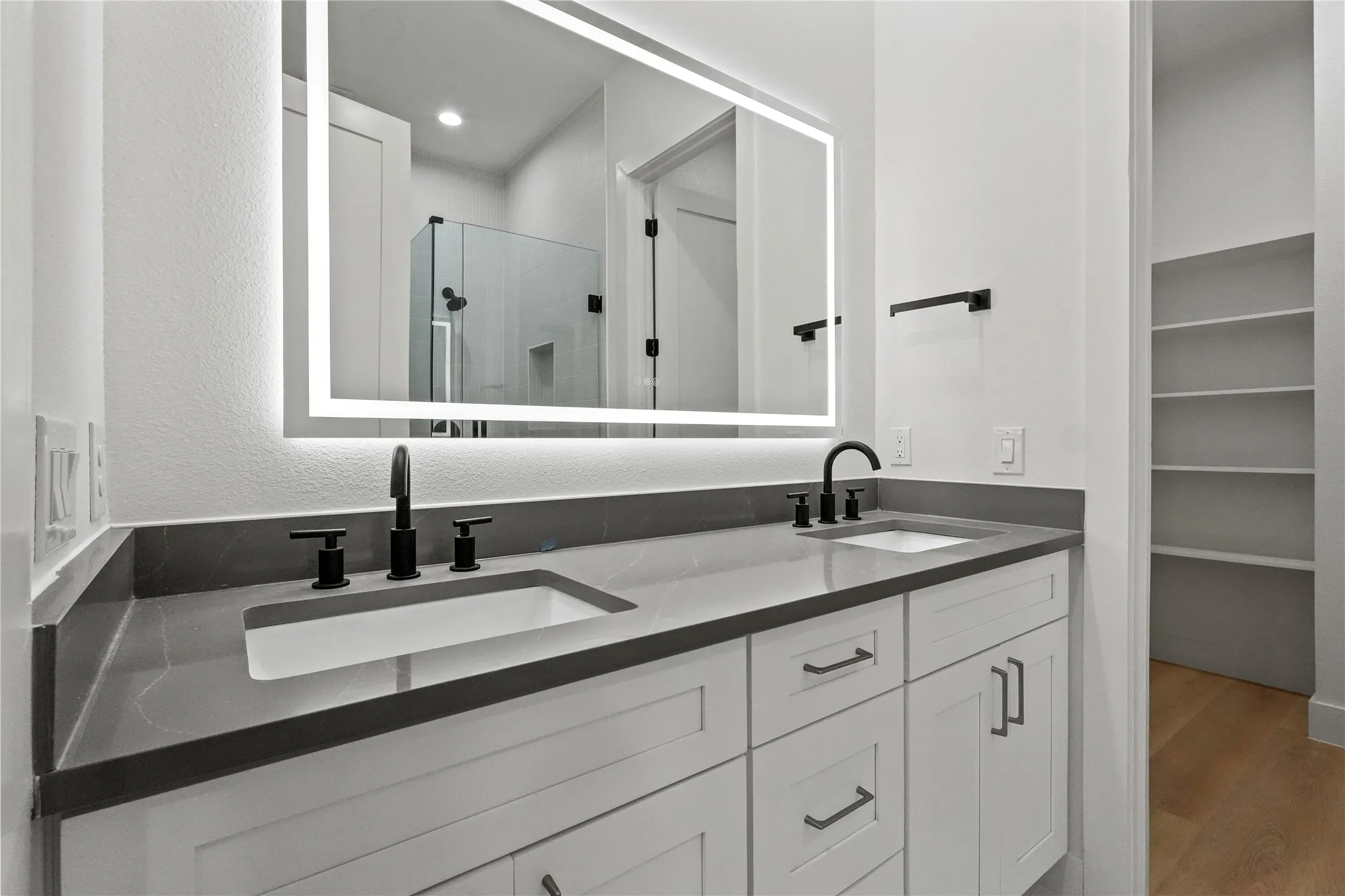 Full bath with a stall shower, double vanity, light wood-style floors, and a walk in closet