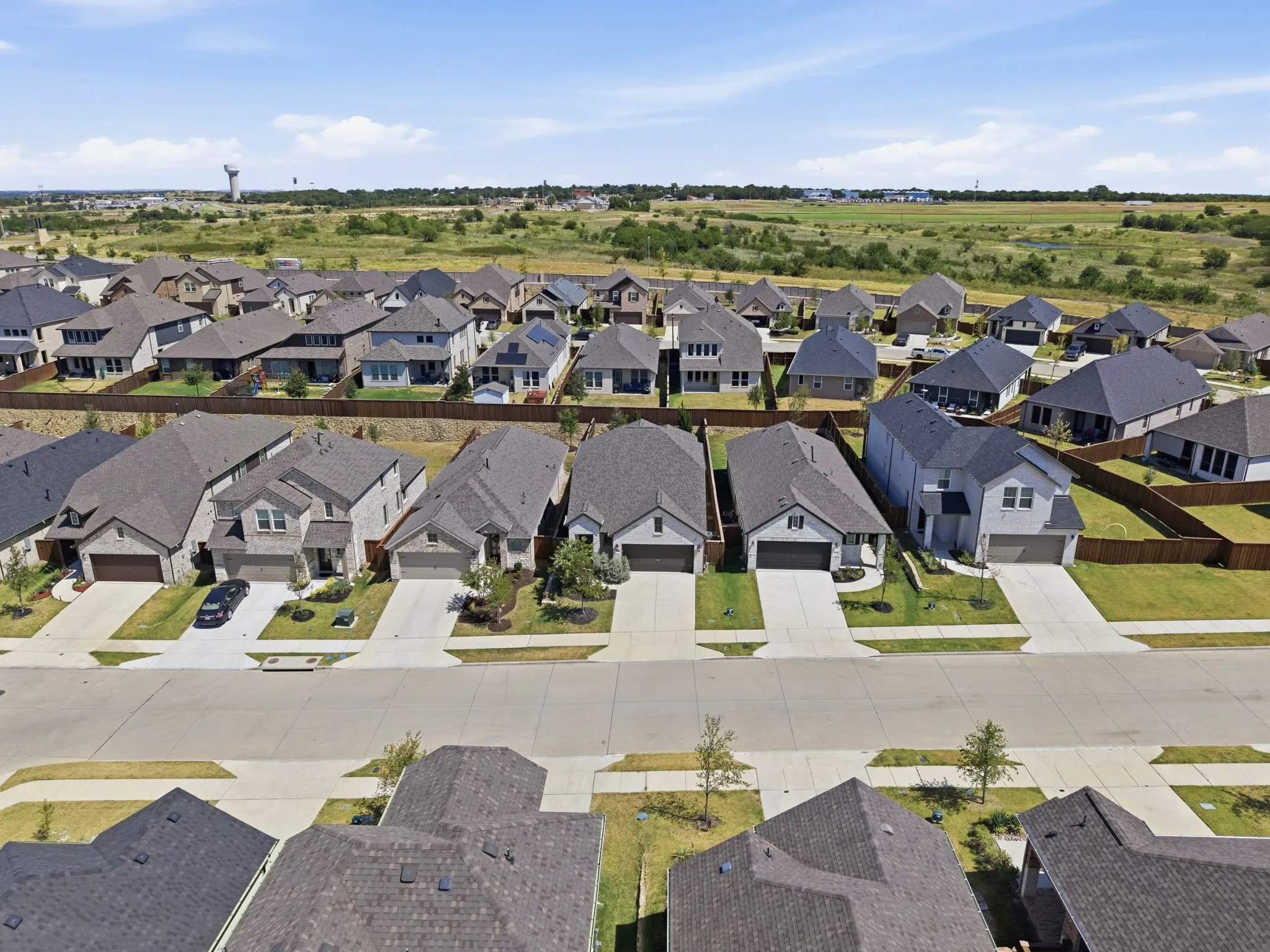 Newly developed residential community featuring a variety of architectural styles, individual fenced properties, and paved streets with sidewalks