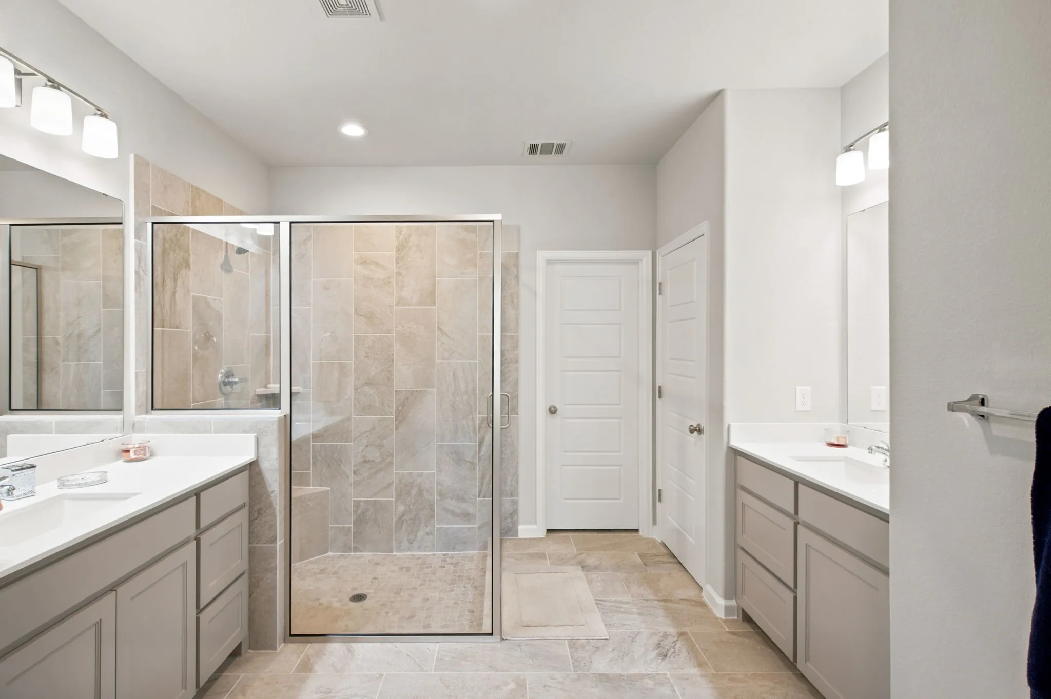 Dual vanity sinks, framed glass shower enclosure, large format tile shower surround, square panel interior doors, and tile flooring