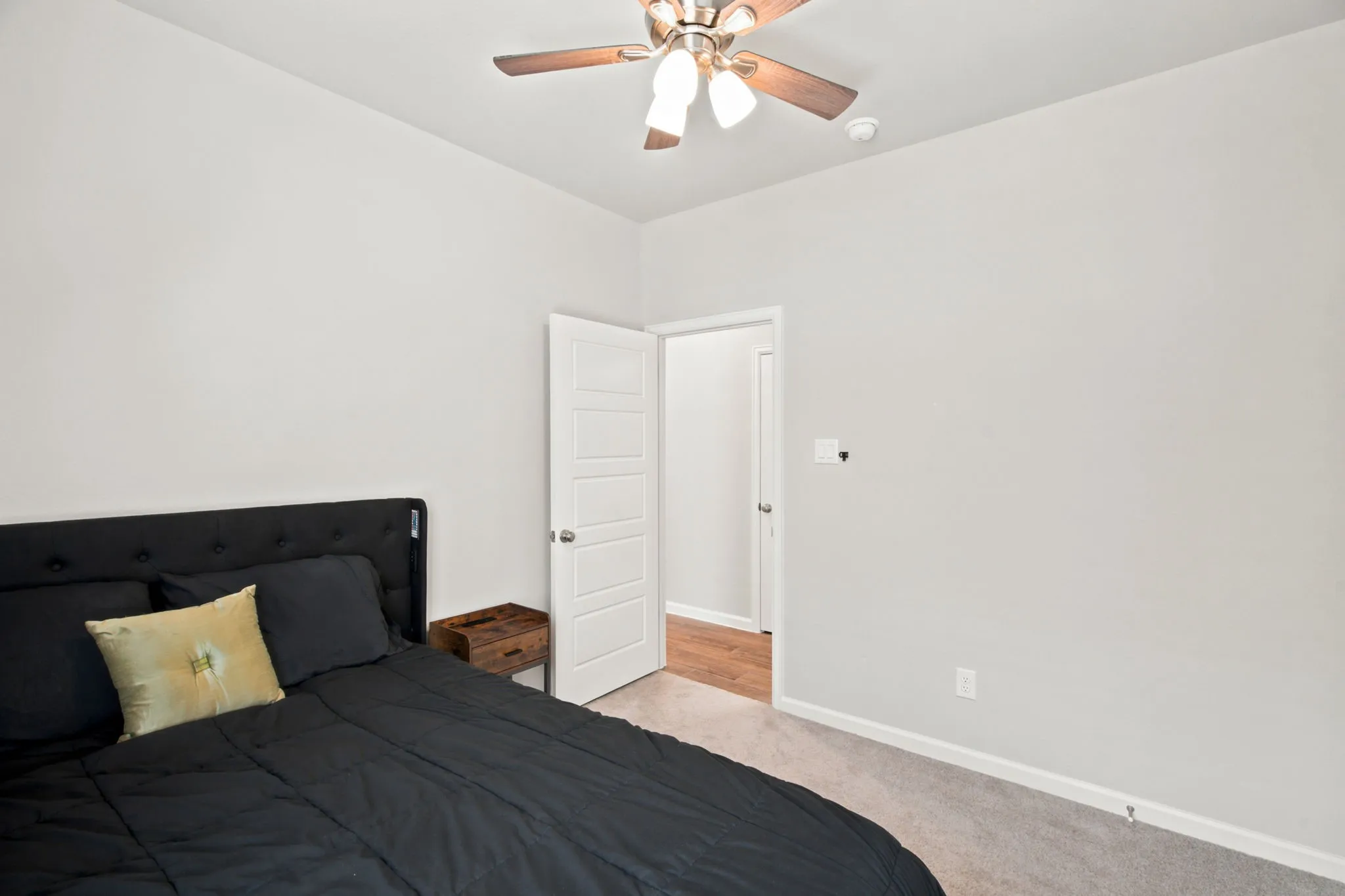 Spacious bedroom featuring neutral wall finishes, wood-finish flooring, and a ceiling fan with integrated lighting