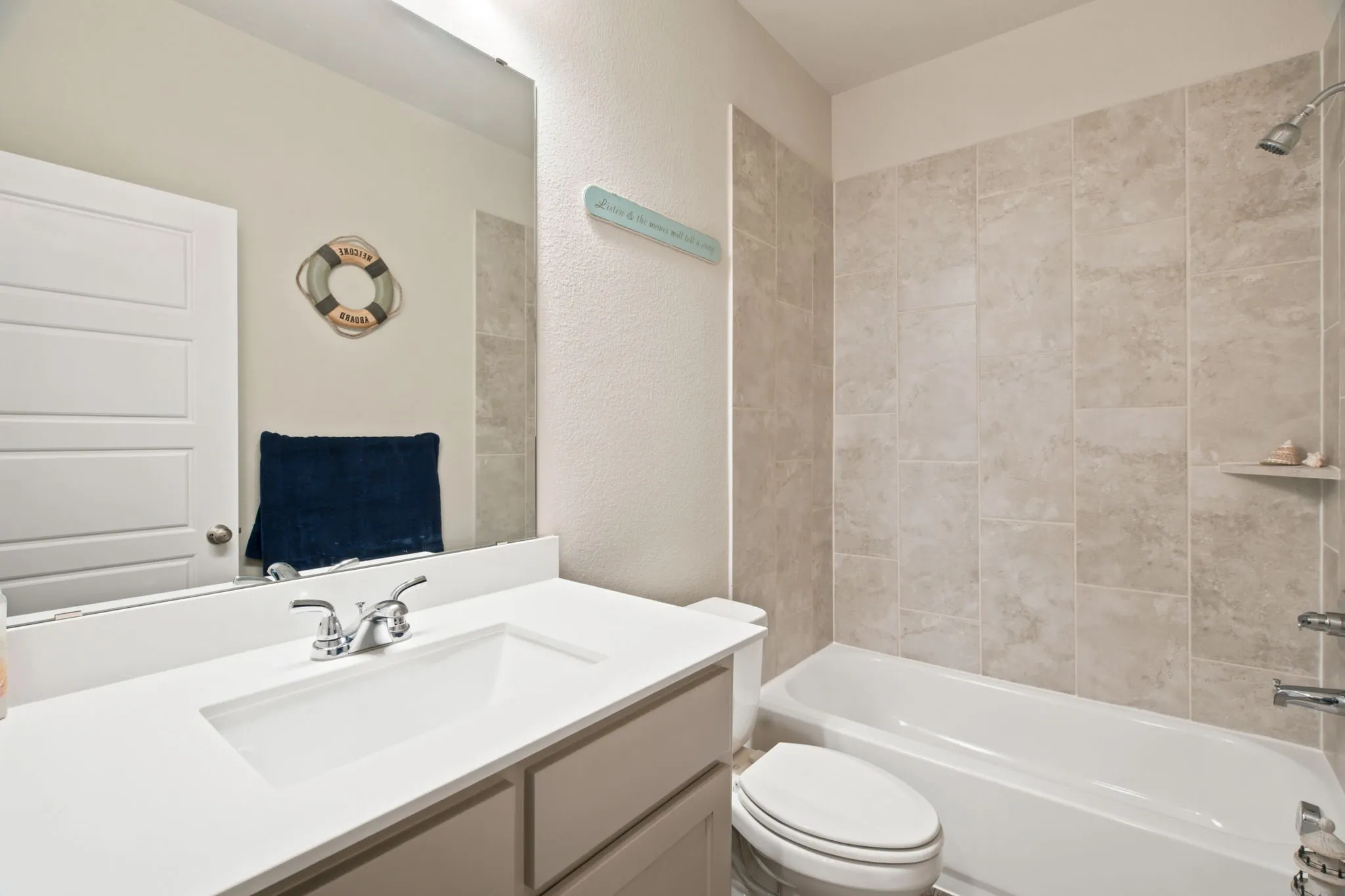 Bathroom featuring a built-in bathtub with shower, tiled shower surround, single vanity with integrated sink, and chrome fixtures