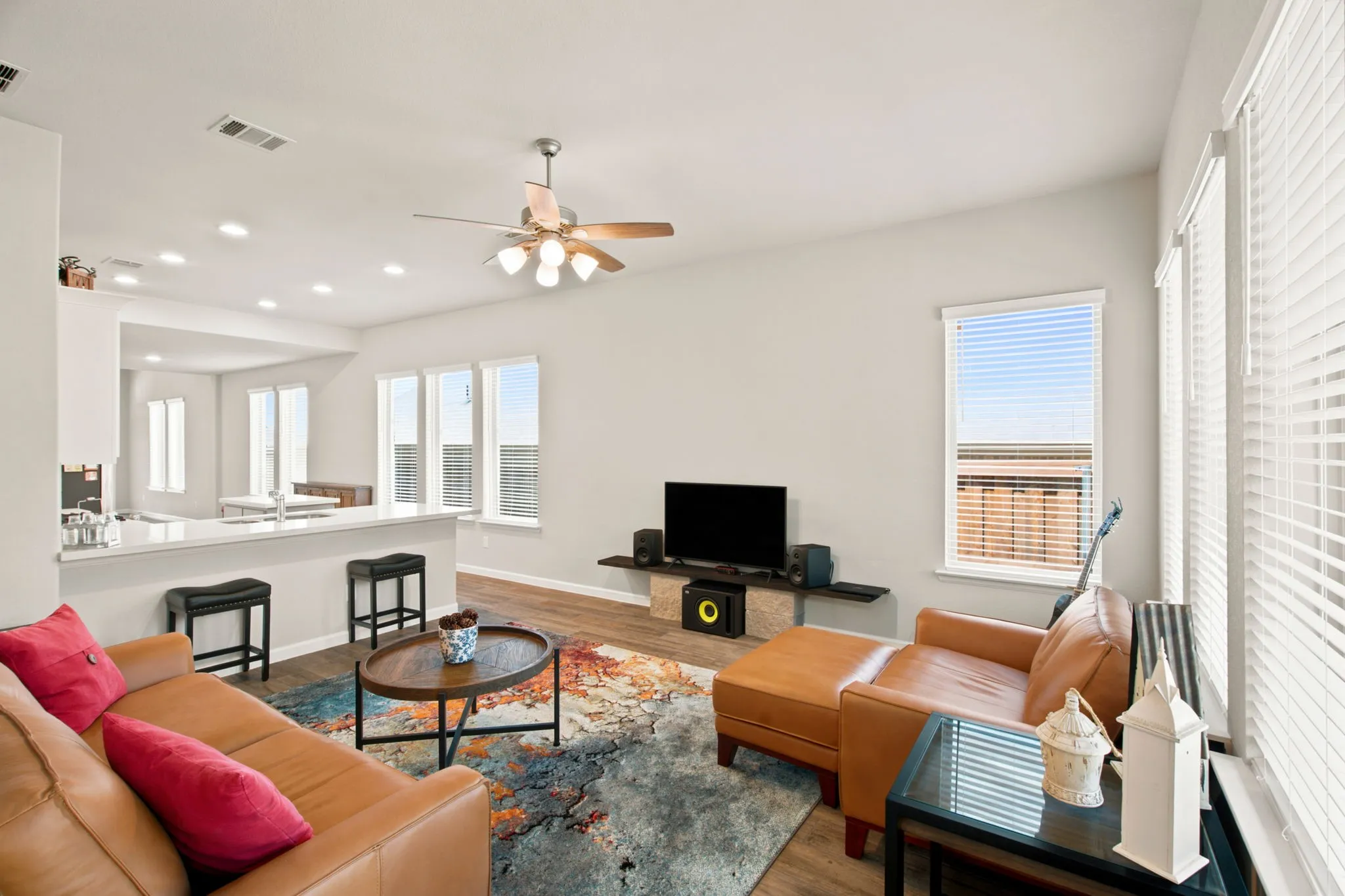 Vaulted ceiling with a ceiling fan, recessed lighting, wood-finish flooring, multiple windows with blinds, and an open-concept layout