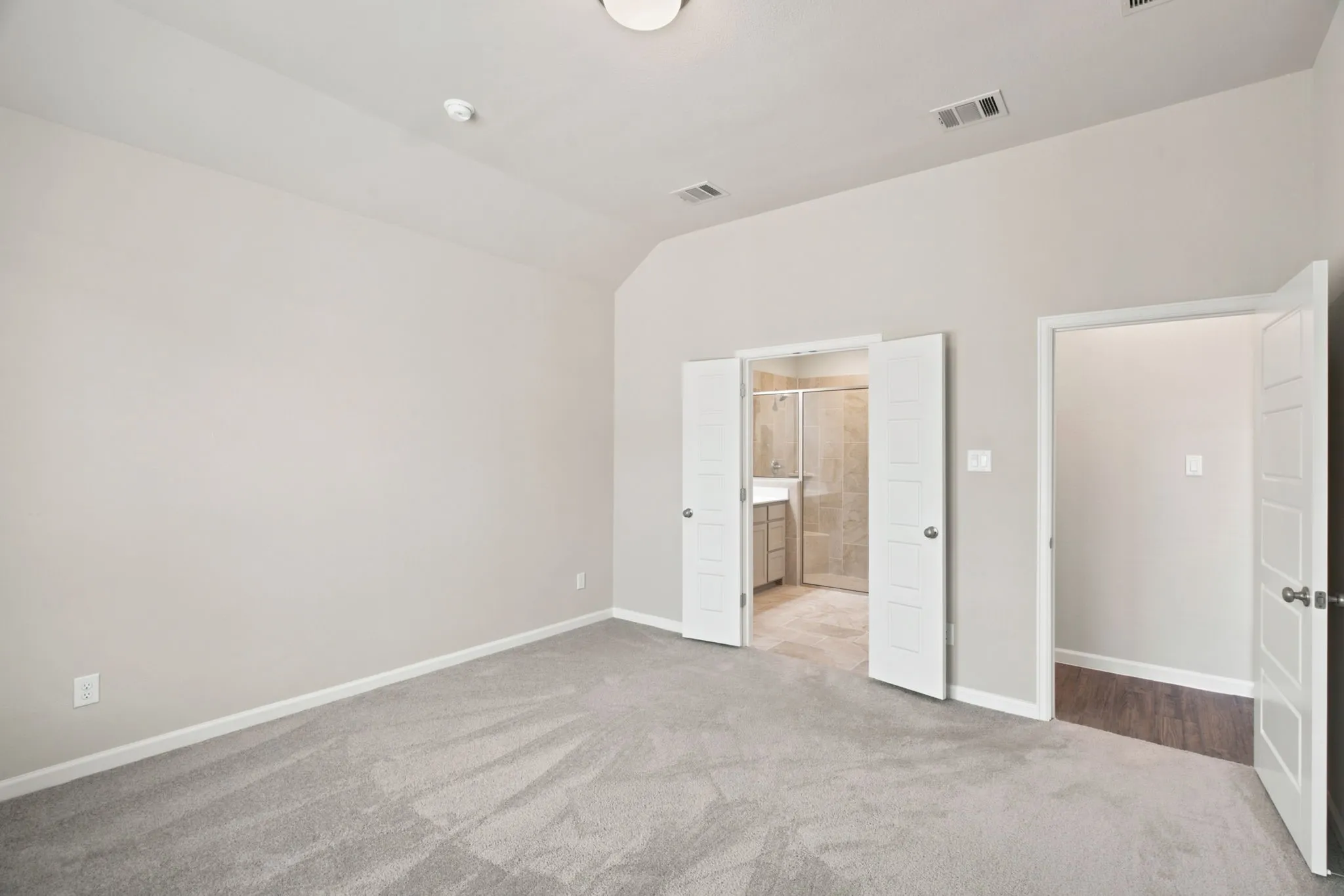 Vaulted ceiling and neutral gray walls with light gray carpeting