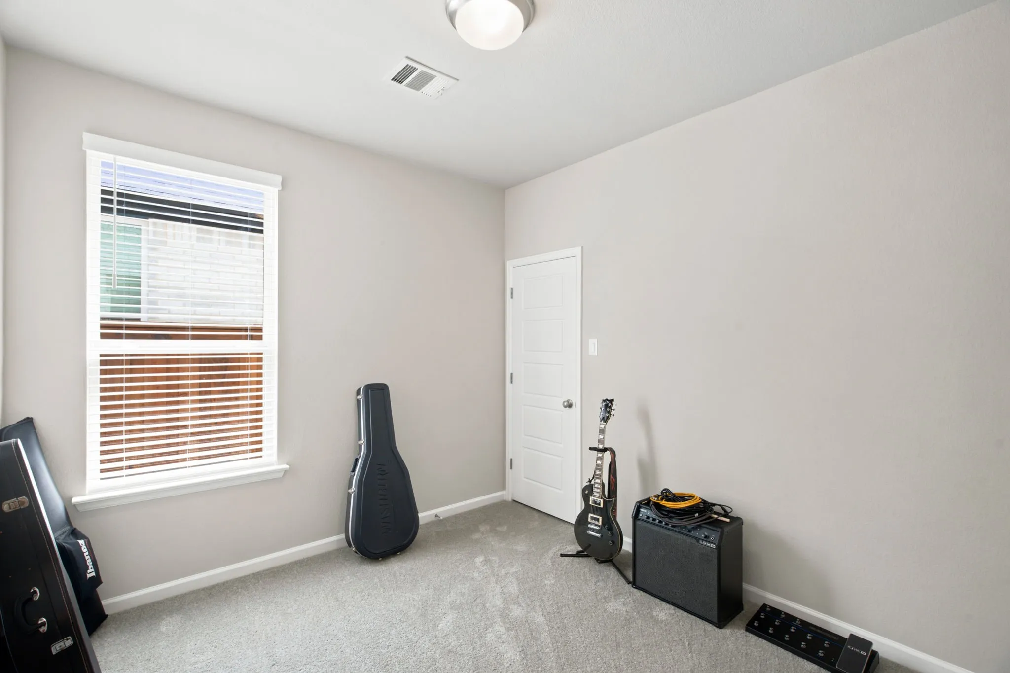 Carpeted room with a single window featuring horizontal blinds