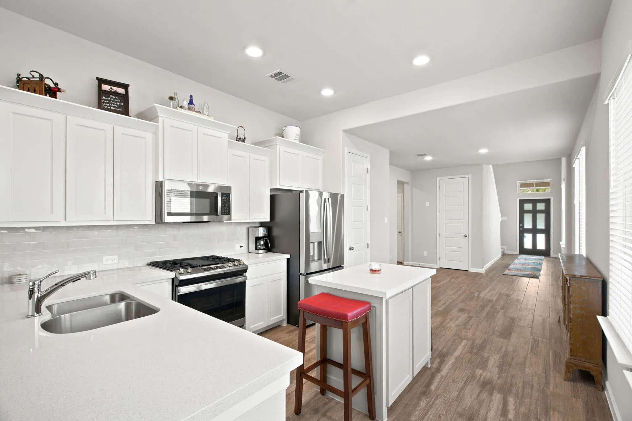 Modern kitchen featuring white cabinetry with ample storage, stainless steel appliances including a gas range and side-by-side refrigerator, quartz countertops, and an undermount sink