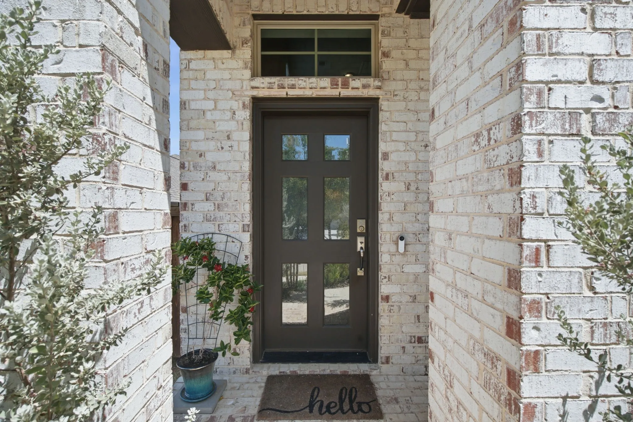 White-washed brick exterior columns, dark paneled entry door with glass inserts, and transom window
