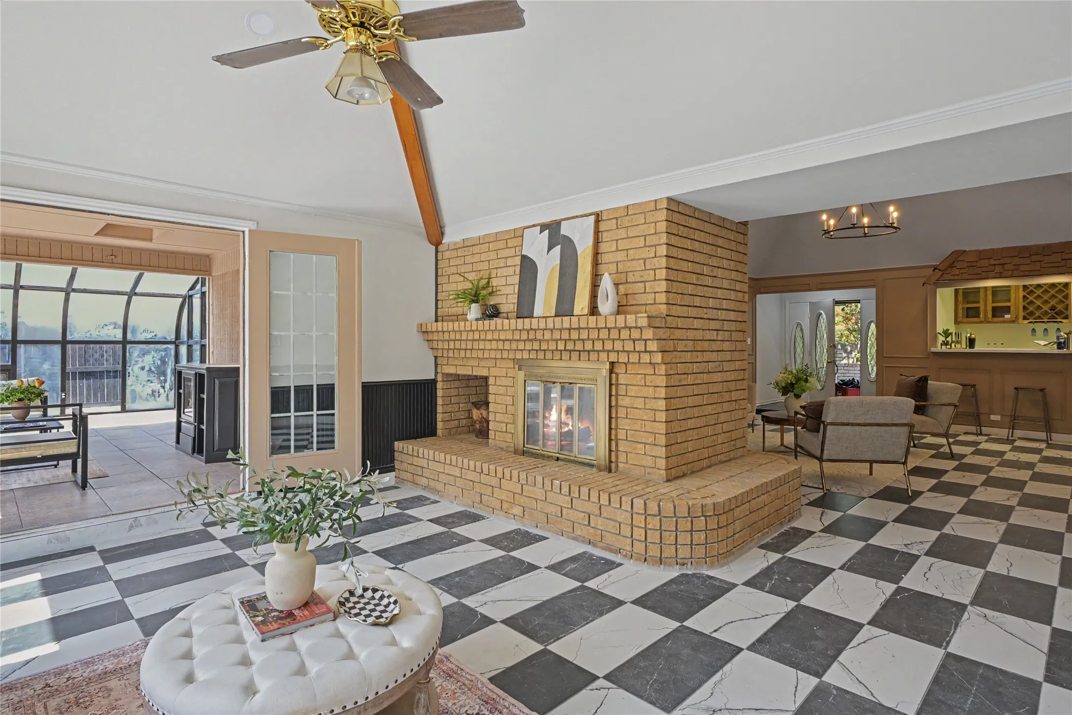 Expansive checkered tile flooring, a prominent brick fireplace, and a built-in wet bar with wine storage
