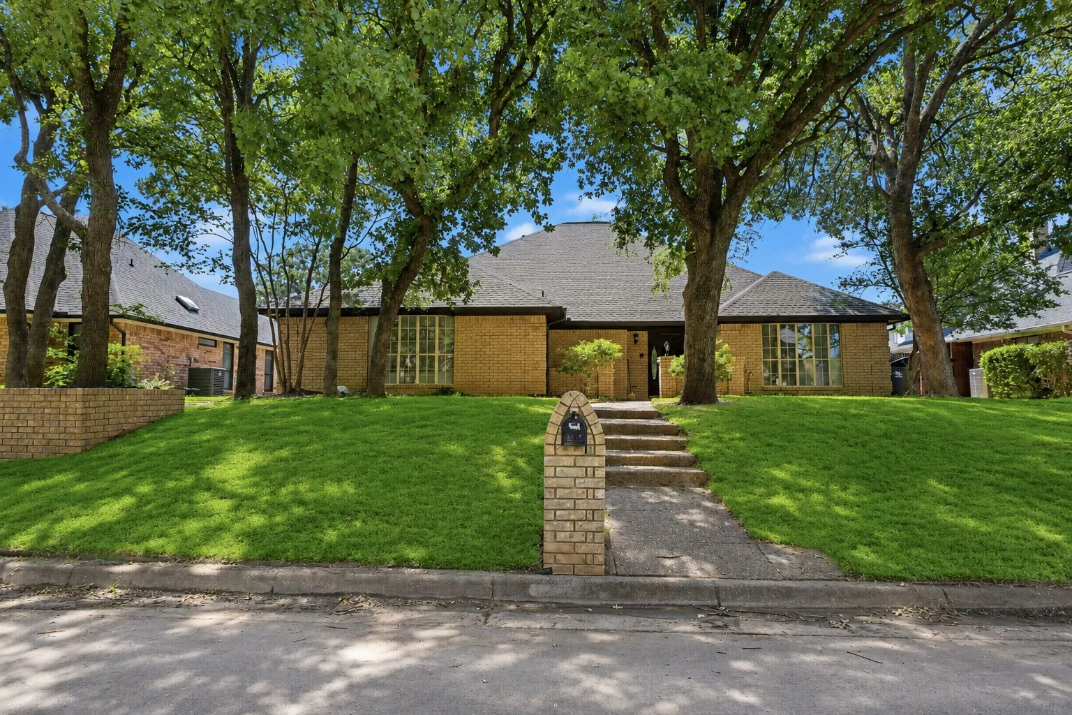 Brick exterior with a dark shingle roof and a concrete walkway