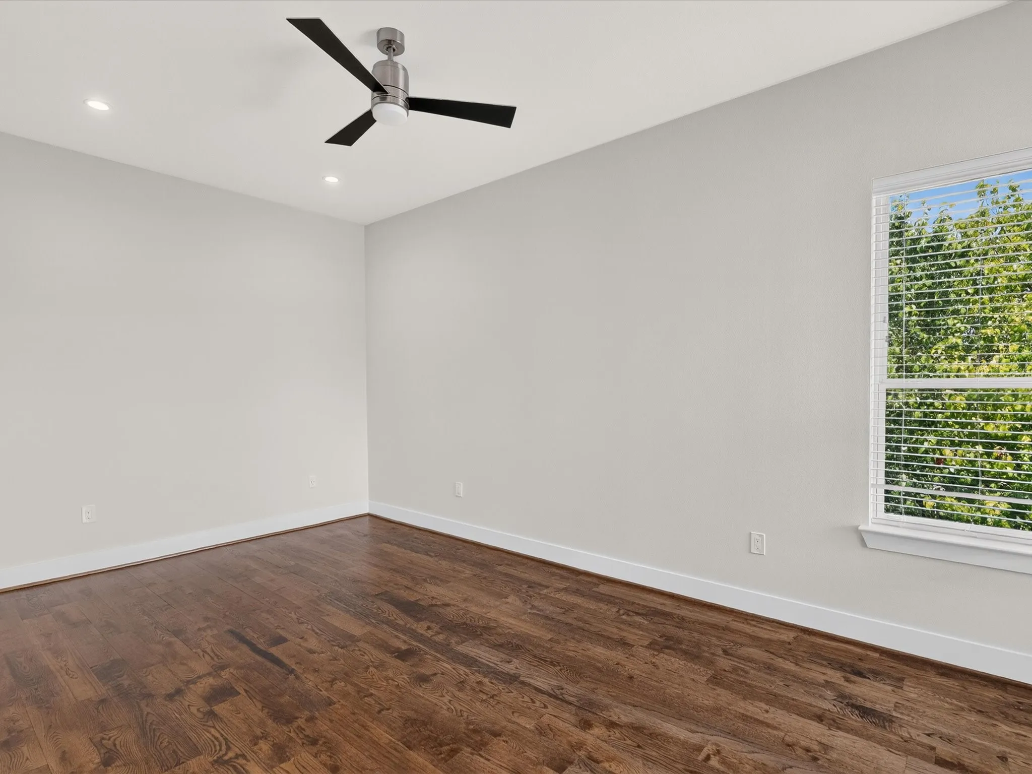 Recessed lighting, dark wood-finish flooring, white walls, white window trim, and a ceiling fan with integrated light