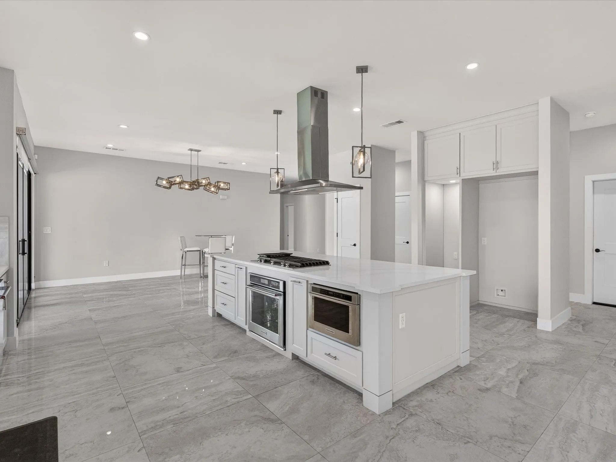 Spacious kitchen featuring a large central island with integrated oven, built-in cooktop, and range hood
