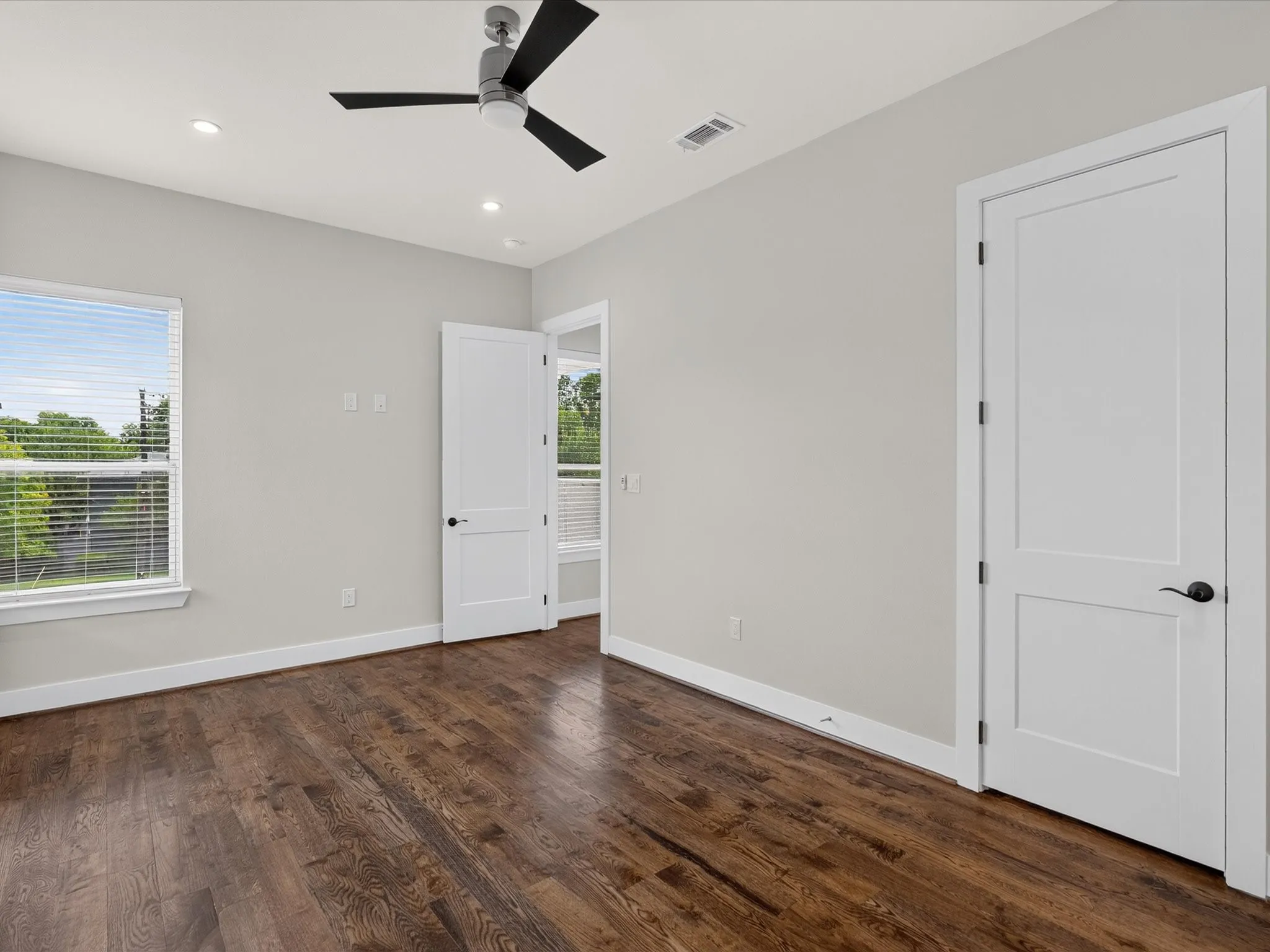 Hardwood flooring, recessed lighting, ceiling fan, white trim, and a paneled door