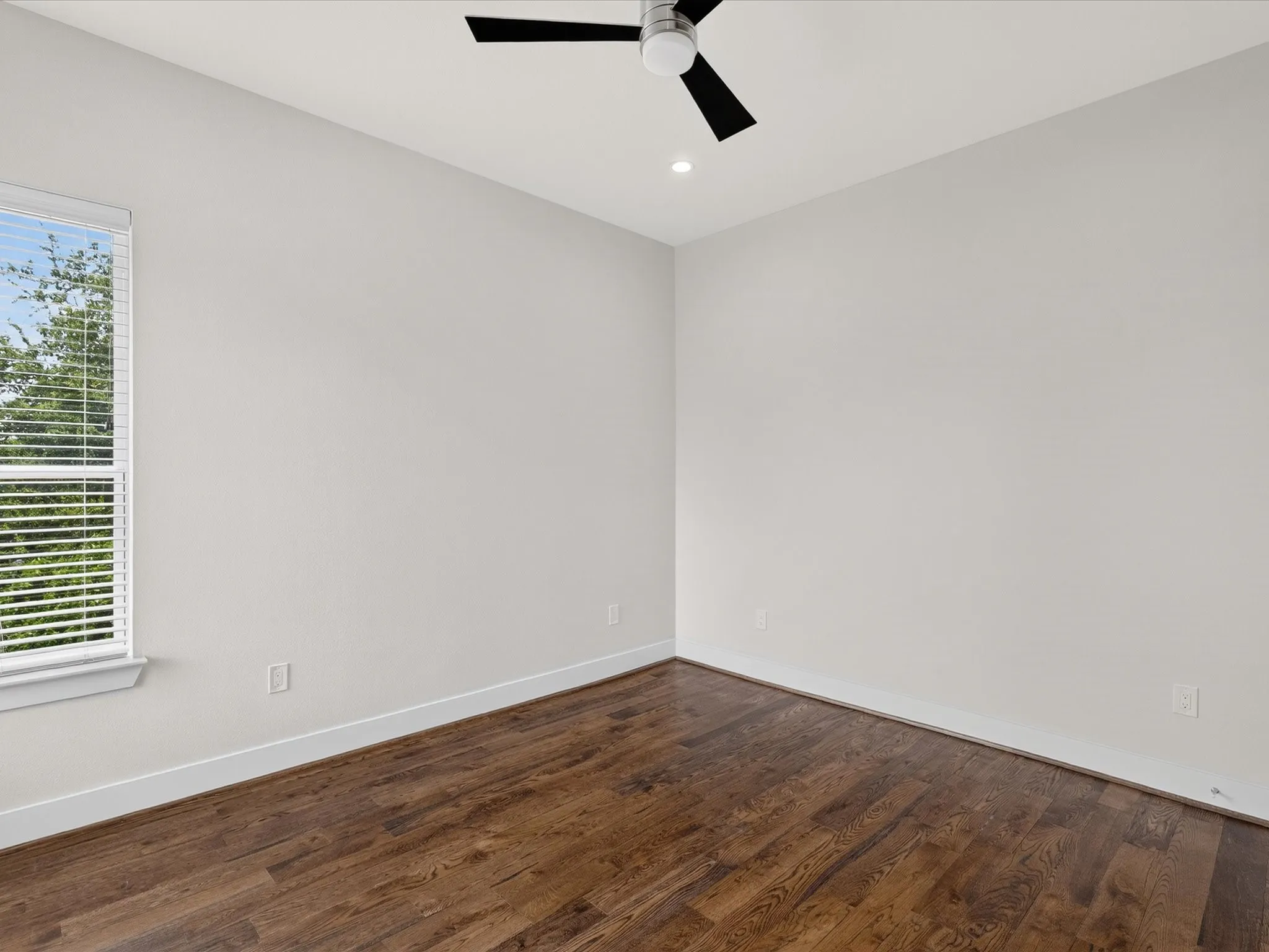 Wood-finish flooring, white walls, window with blinds, recessed ceiling light, and a ceiling fan