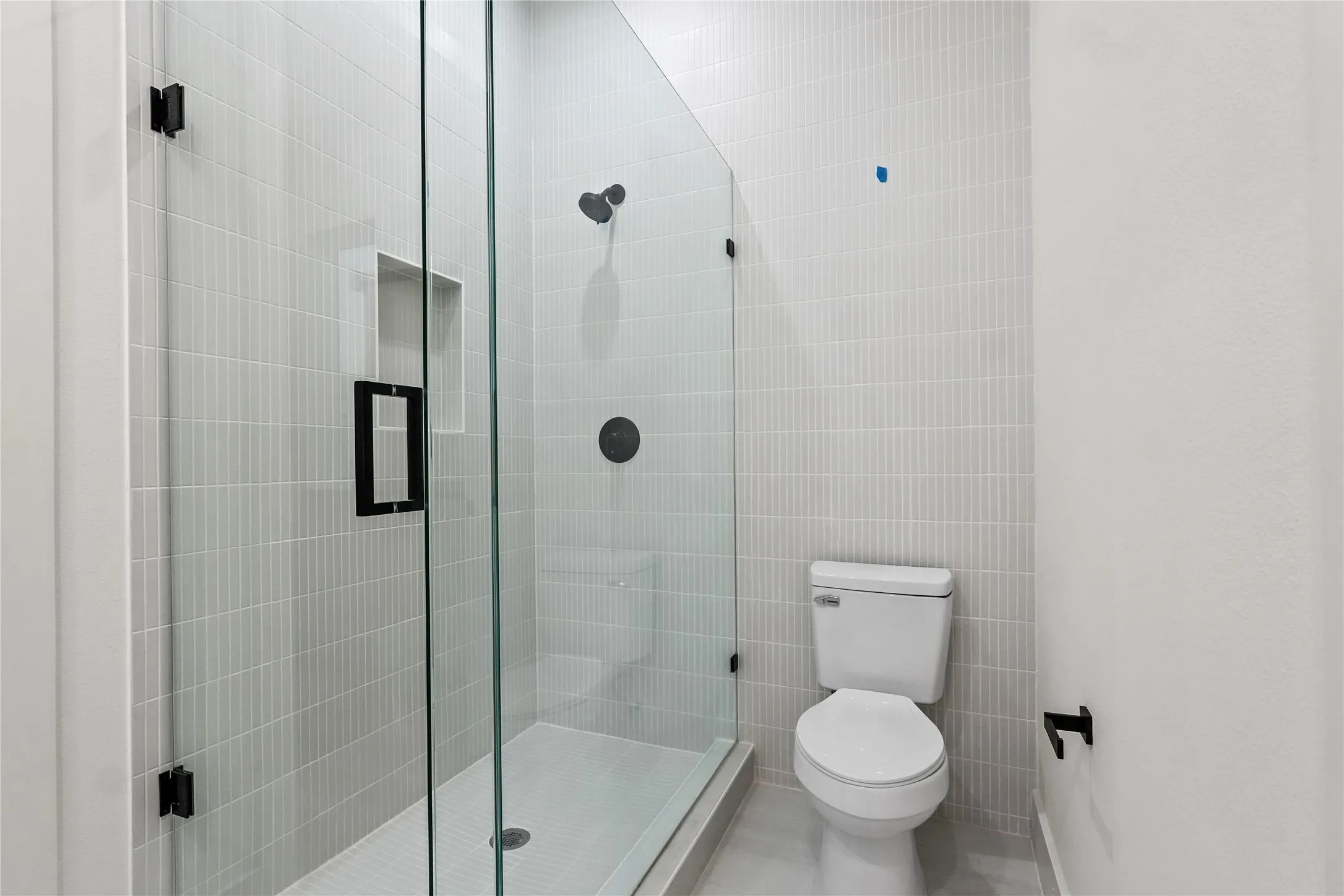 Bathroom featuring a shower stall and tile walls