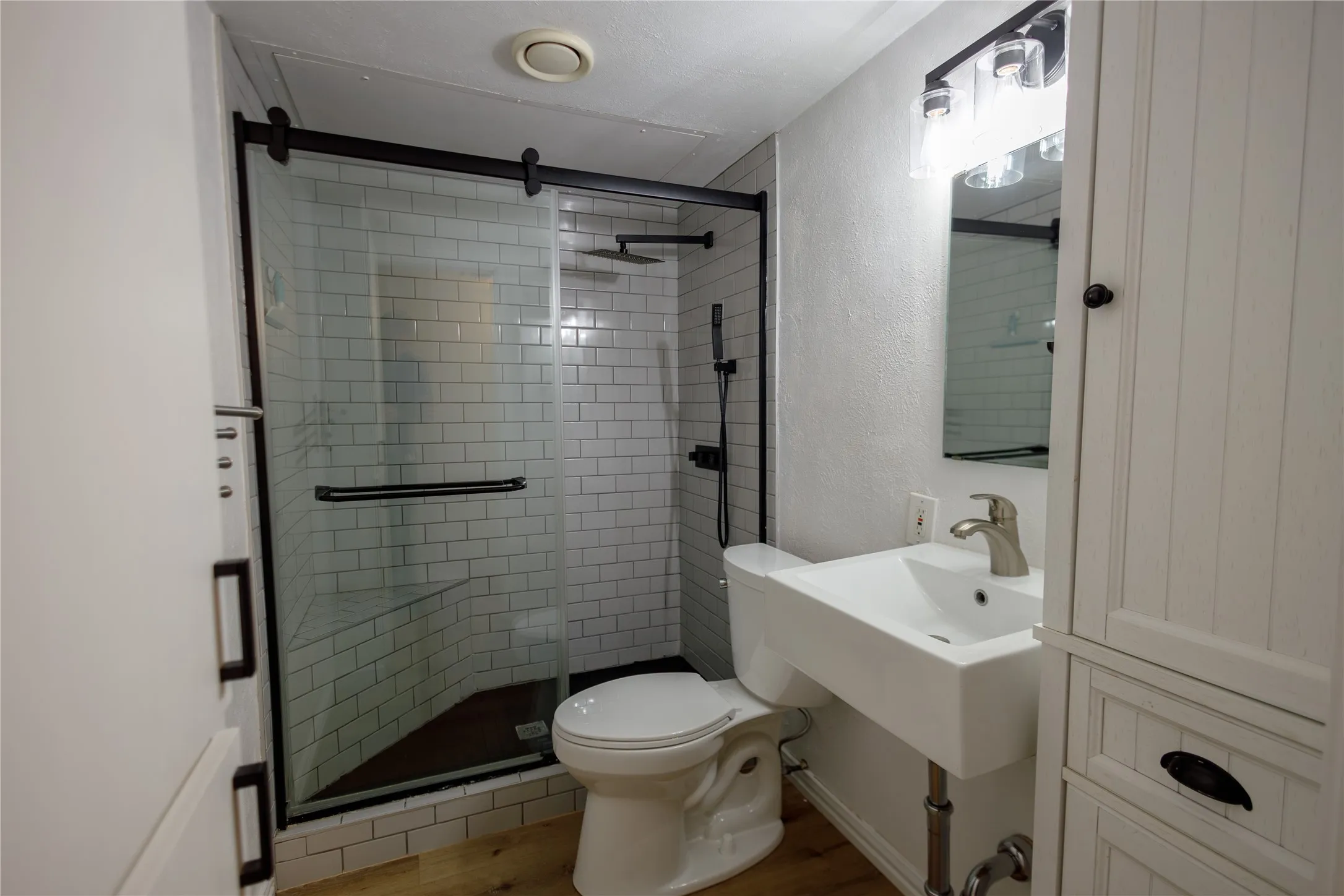 Shower with subway tile surround, sliding glass door, and a built-in bench