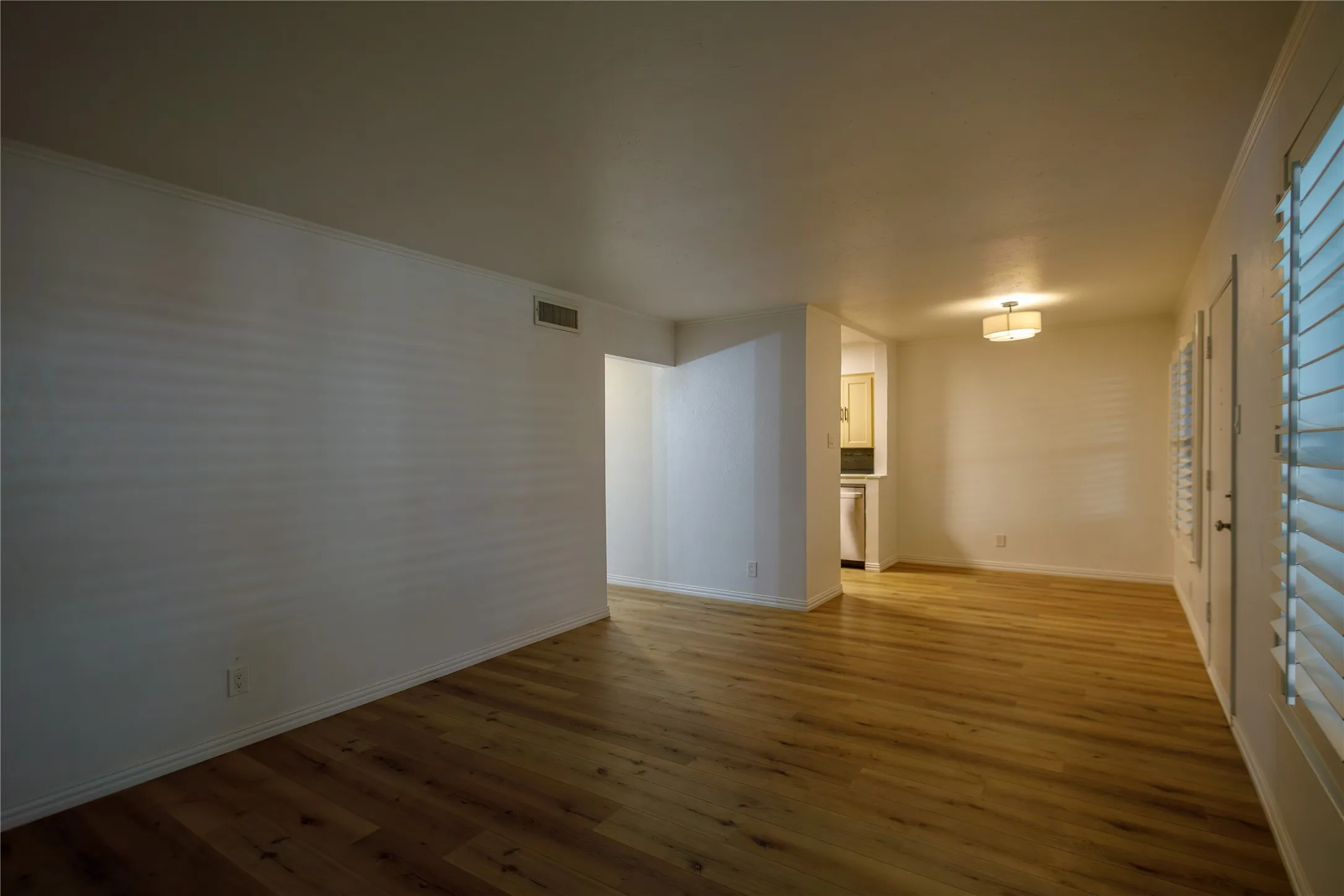 Wood-finish flooring throughout, white painted walls, and a semi-flush mount ceiling light fixture